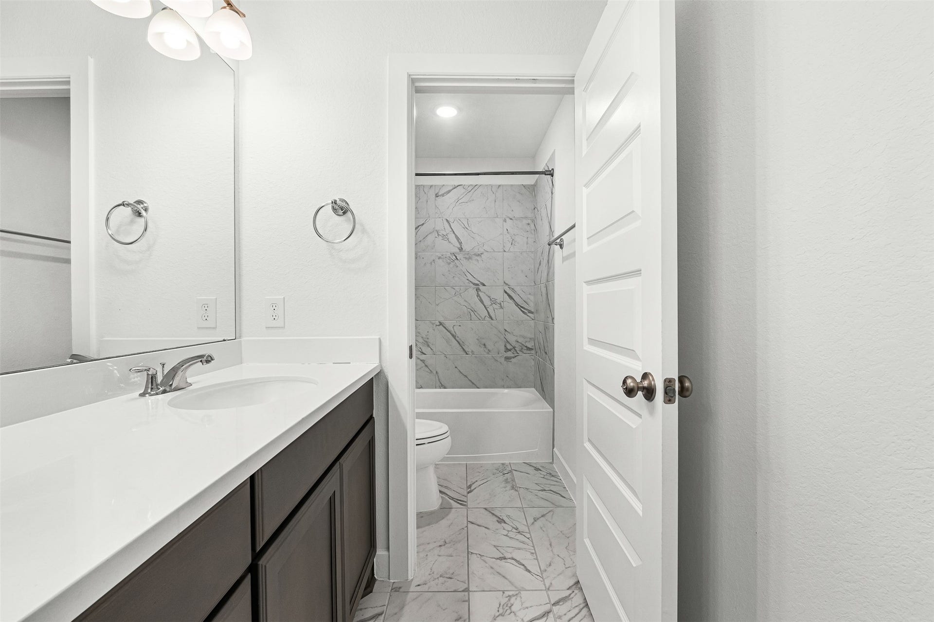28314 Emerald Bend, Spring, TX 77386 Refined marble-look tile flooring connects the spacious vanity area to a private water closet and tub-and-shower combination. A dark wood-look vanity with crisp white quartz countertops and sleek chrome fixtures adds modern function to this full bathroom.