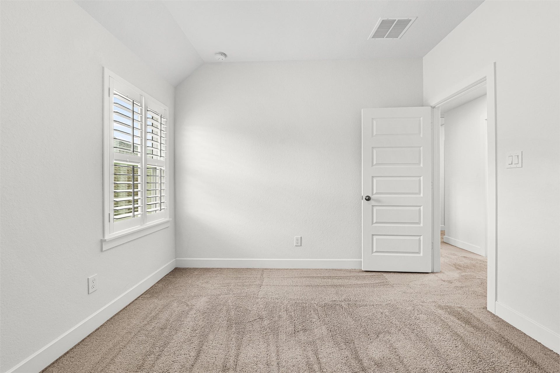 28314 Emerald Bend, Spring, TX 77386 Clean plantation shutters frame the window in this secondary bedroom, featuring soft carpet flooring and classic neutral walls. A versatile layout and sloped ceiling details provide a peaceful space for rest or personalized furnishings.