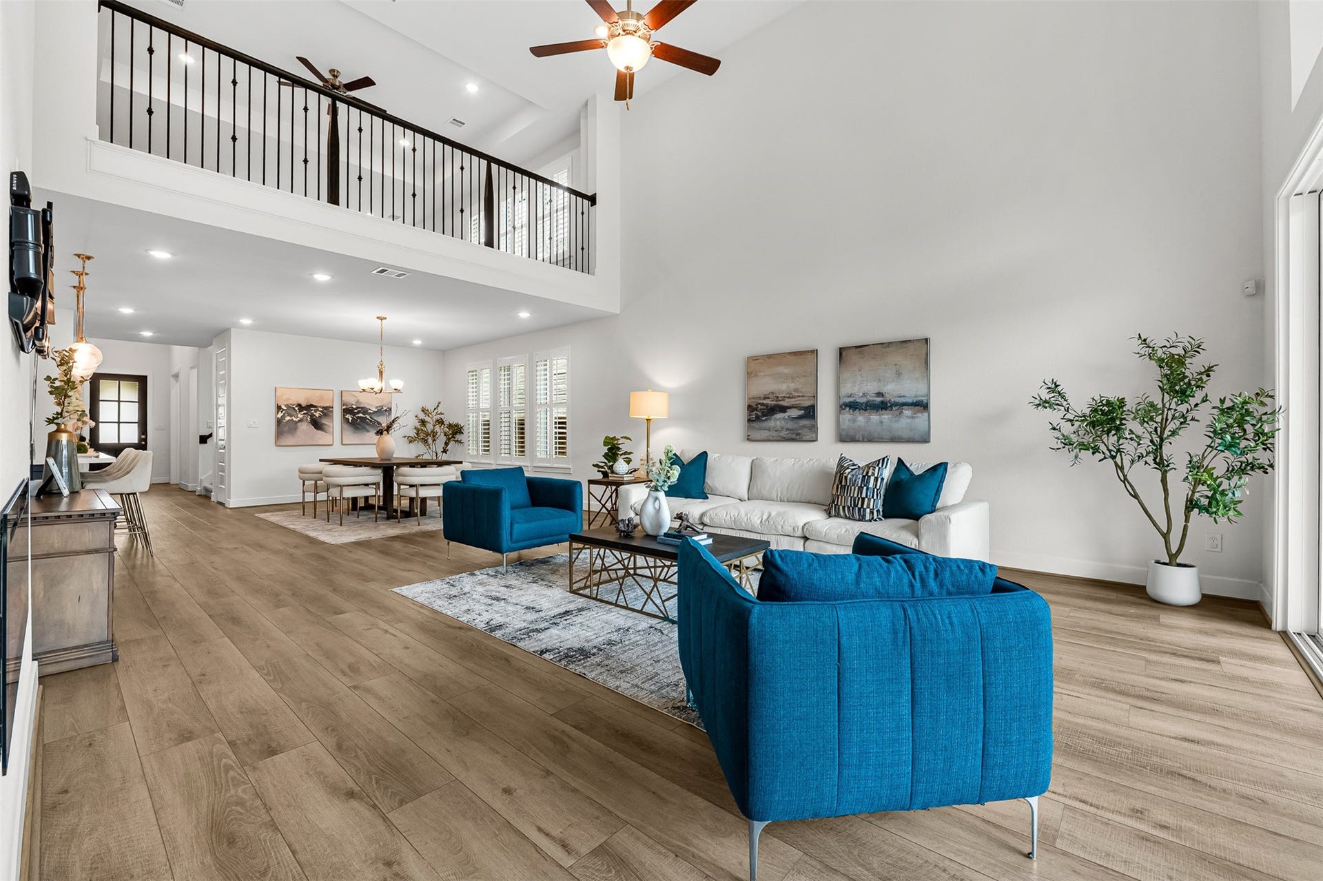 28314 Emerald Bend, Spring, TX 77386 Soaring double-height ceilings and a dramatic second-floor overlook anchor this open-concept main living area. Wood-look flooring flows effortlessly toward the adjoining dining space, while expansive sliding glass doors provide direct patio access.