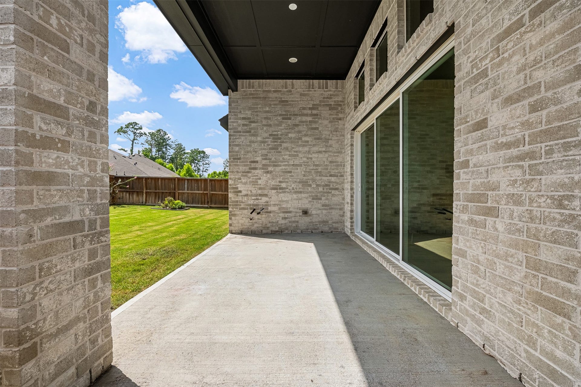 28314 Emerald Bend, Spring, TX 77386 Extending from the home's rear exterior, this covered concrete patio provides an inviting shelter for outdoor relaxation. Soaring brick walls and dark tongue-and-groove ceiling accents frame the space, offering direct access to the lush green lawn and expansive sliding glass doors.