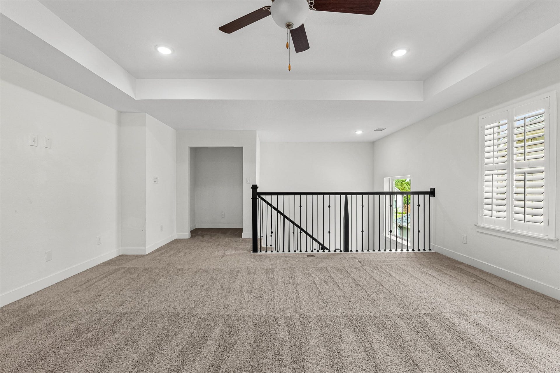 28314 Emerald Bend, Spring, TX 77386 Wrought-iron railings overlook the lower level from this expansive second-floor game room featuring a tray ceiling and plush carpet. Plantation shutters frame the window, while a recessed alcove provides a quiet nook for desk placement or extra storage.