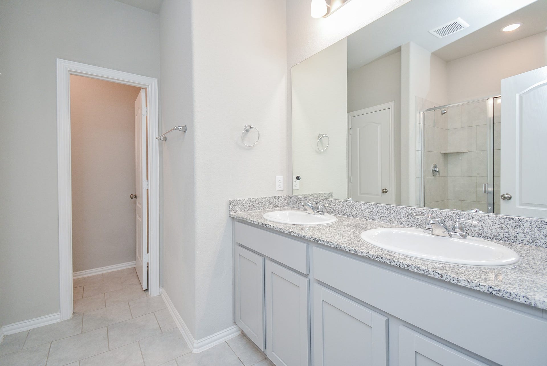 7450 French Quarter Court, Fulshear, TX 77441 The primary ensuite bath offers a relaxing tone-on-tone theme, with double sinks, a sparkling wall-wide mirror and simple contemporary lighting above..