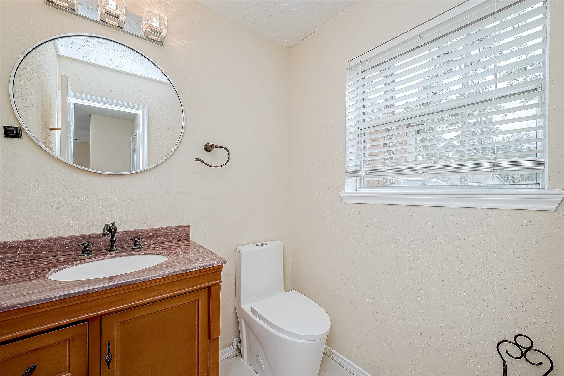 The wooden vanity adds warmth and charm to this half bathroom. A practical yet stylish space for guests and daily use.