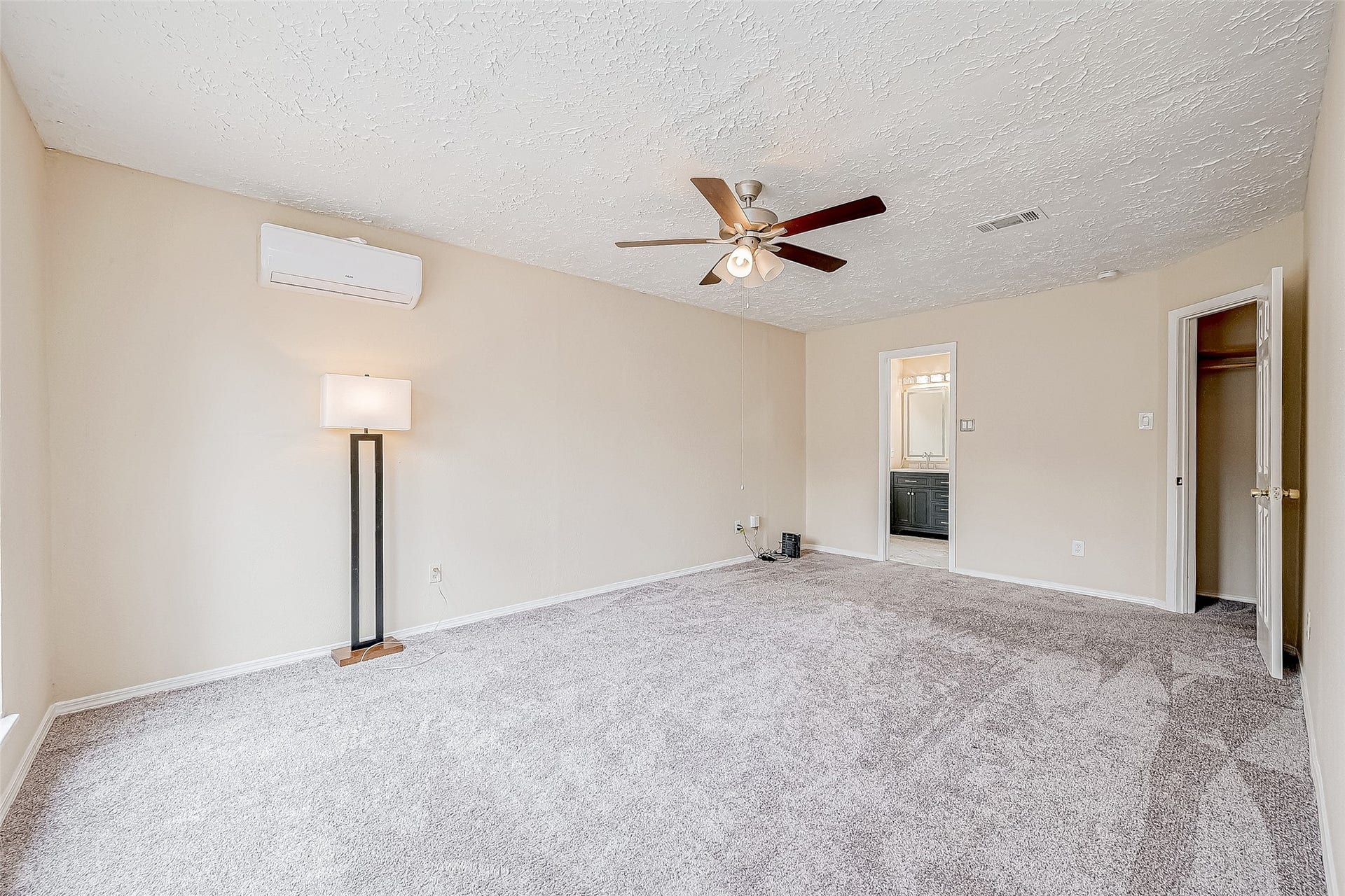 The primary bedroom is a spacious haven, offering a large window with views of the yard, soft carpeting underfoot, and a ceiling fan for optimal comfort. The attached en suite bathroom completes the space with elegance and convenience.