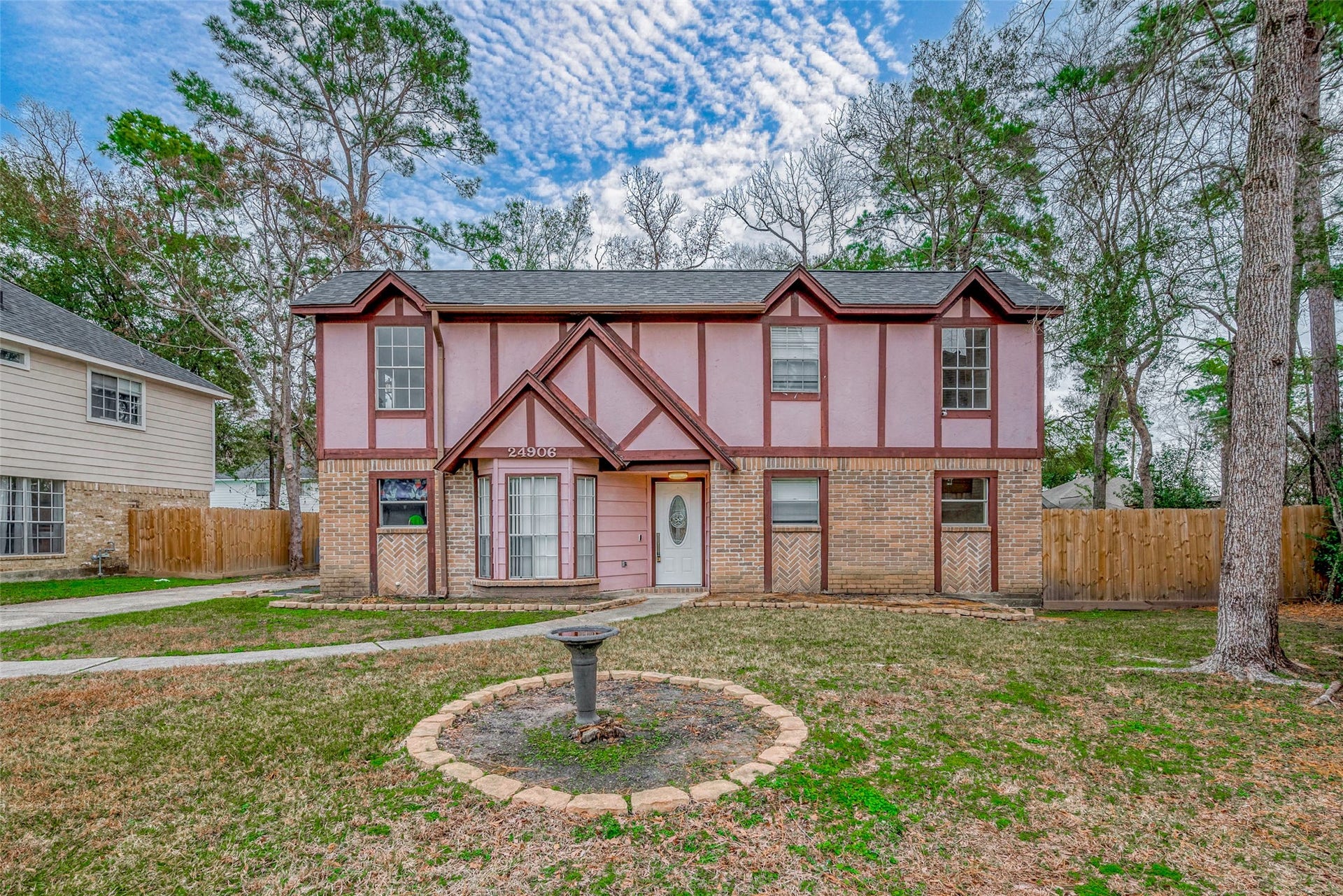 Nestled in a peaceful cul-de-sac, this home boasts a striking exterior that pairs classic brickwork with natural wood elements. The expansive front yard is framed by a long driveway and a walkway that gracefully cuts through the lush, green lawn, guiding you toward the front entrance.