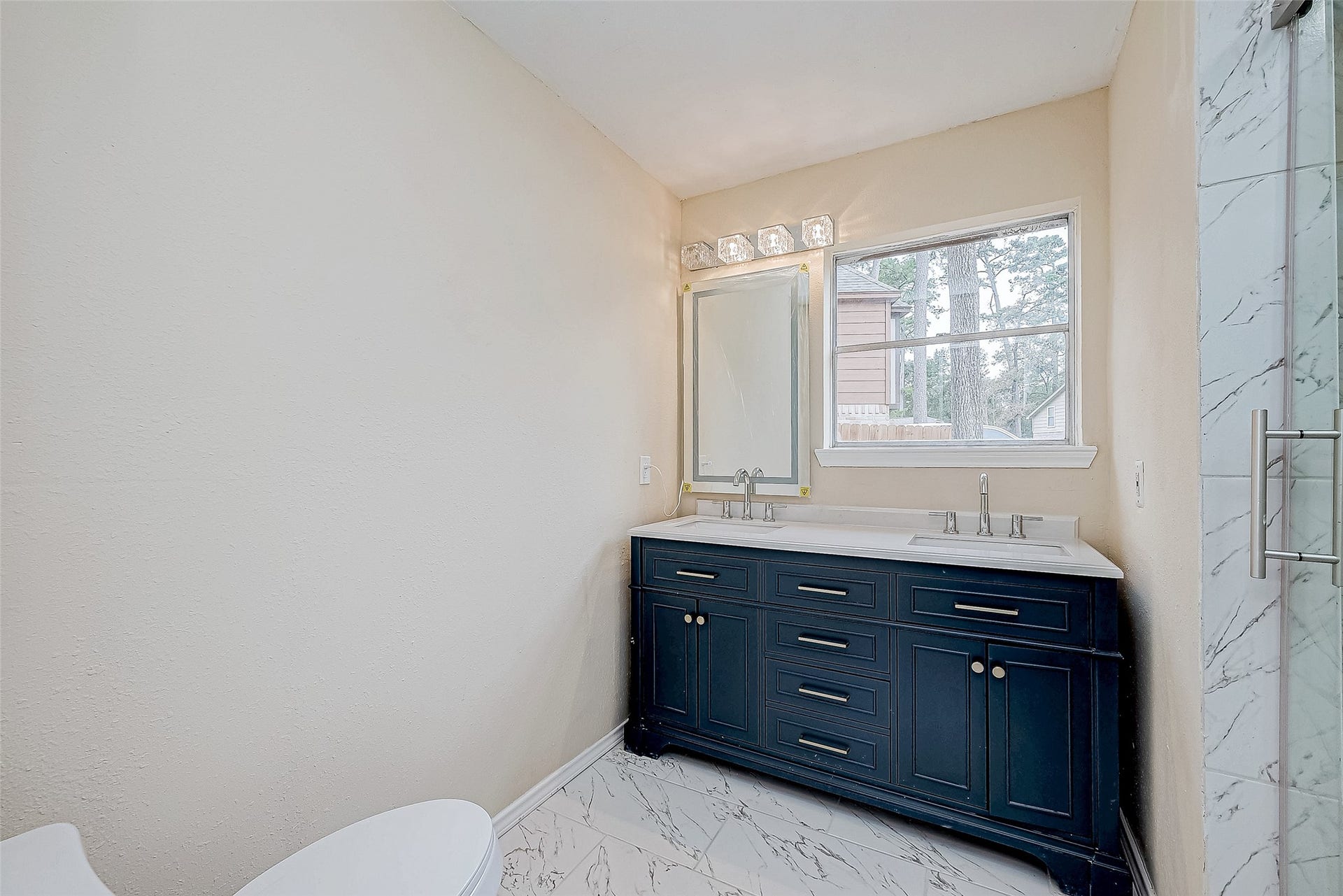 This spacious en suite bathroom features a glass-enclosed shower and a dual-sink vanity. Its thoughtful layout blends timeless design with everyday practicality.