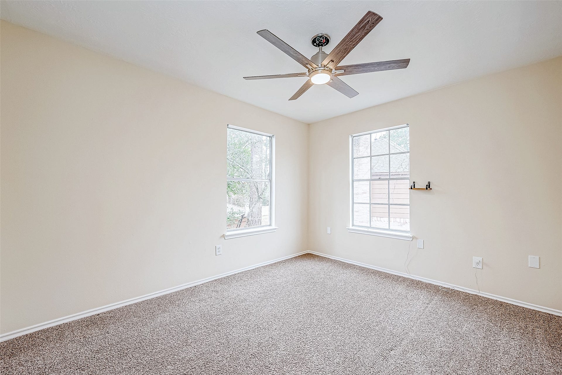 This bedroom is both spacious and inviting, featuring soft carpeting, large windows that frame outdoor views, and a ceiling fan for added comfort. A well-sized closet provides ample storage.