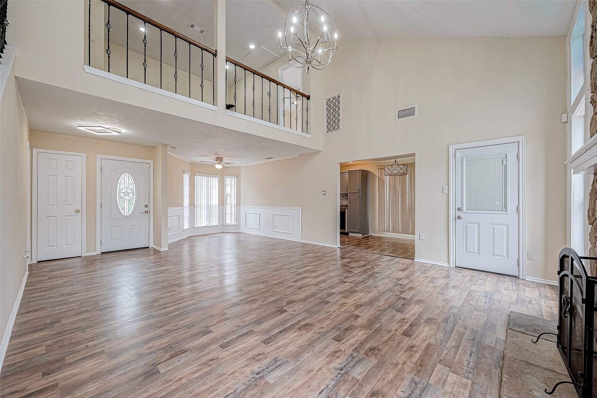 This angle showcases the fluid connectivity of the home, with a view of the entryway, staircase, and a peek into the kitchen. The expansive space feels cohesive yet distinct, offering a seamless flow between the living room and adjacent areas.