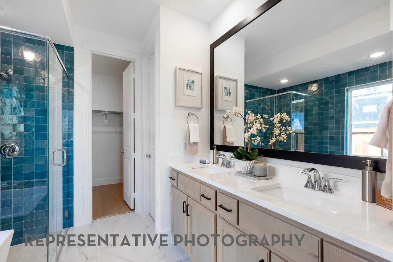 A primary bathroom with dual sinks, a large mirror, and a window combines natural light with functional design for a bright comfortable space.