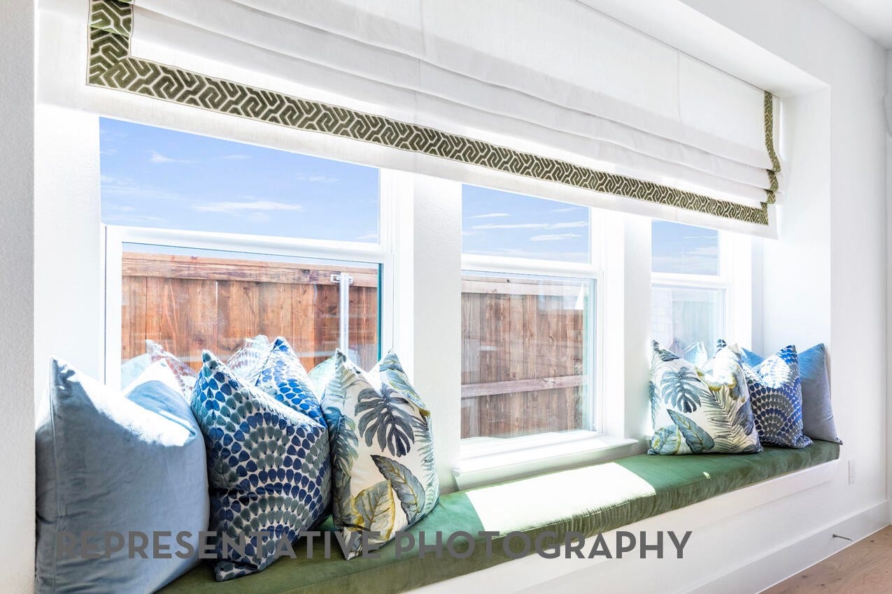 A cozy kitchen window seat nestled beneath wide windows creates a bright, inviting nook filled with natural light and views of the outdoors.