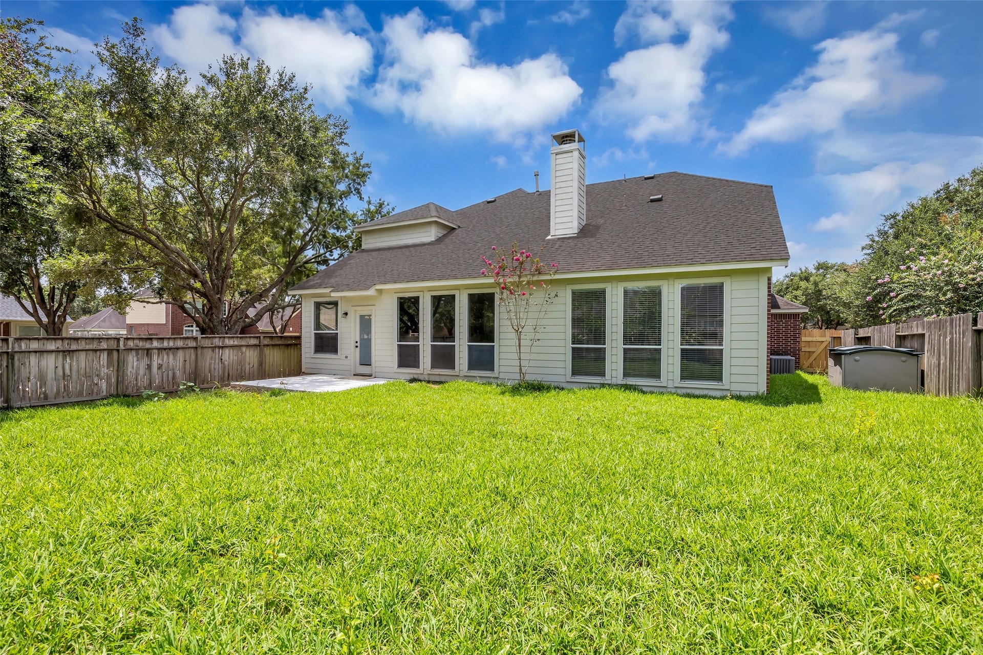 22002 Madera Canyon Court, Richmond, TX 77469 Spacious backyard with lush greenery, tall privacy fencing, and a charming patio area perfect for outdoor relaxation.
