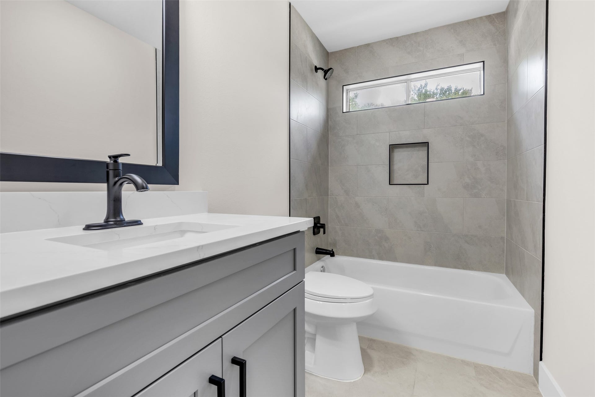 22002 Madera Canyon Court, Richmond, TX 77469 Modern bathroom featuring a sleek vanity with a black faucet, a bathtub with elegant tile surround, and a high window for natural light.