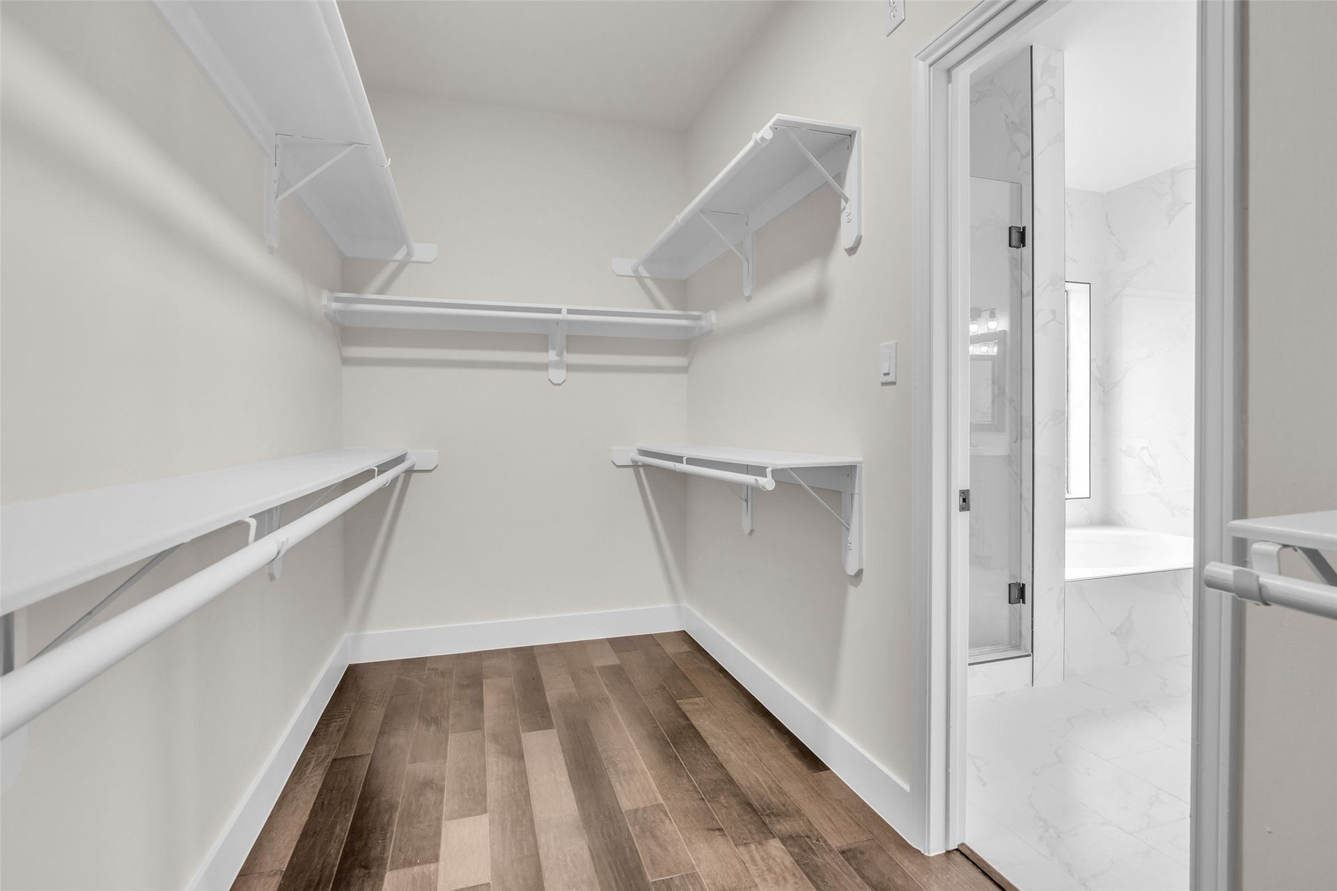 22002 Madera Canyon Court, Richmond, TX 77469 Spacious primary walk-in closet with ample shelving and hanging space, featuring elegant hardwood floors and an adjacent luxurious bathroom.