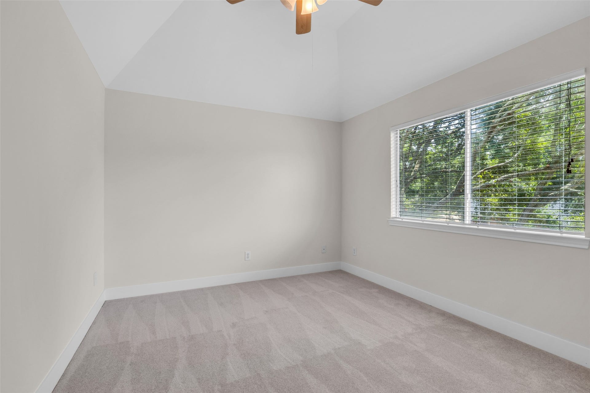 22002 Madera Canyon Court, Richmond, TX 77469 Bright and spacious first bedroom with vaulted ceilings, large window with serene views, and plush carpeting, perfect for a cozy retreat.