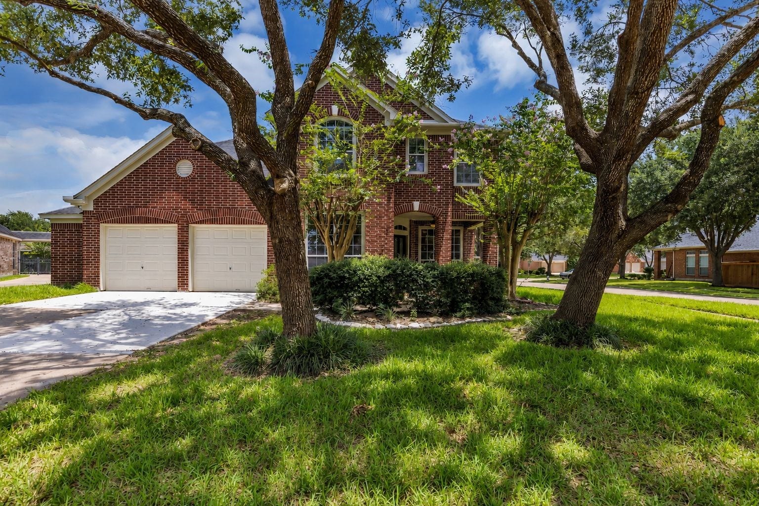 22002 Madera Canyon Court, Richmond, TX 77469 Charming two-story brick home with a welcoming front yard shaded by mature trees and a spacious two-car garage.