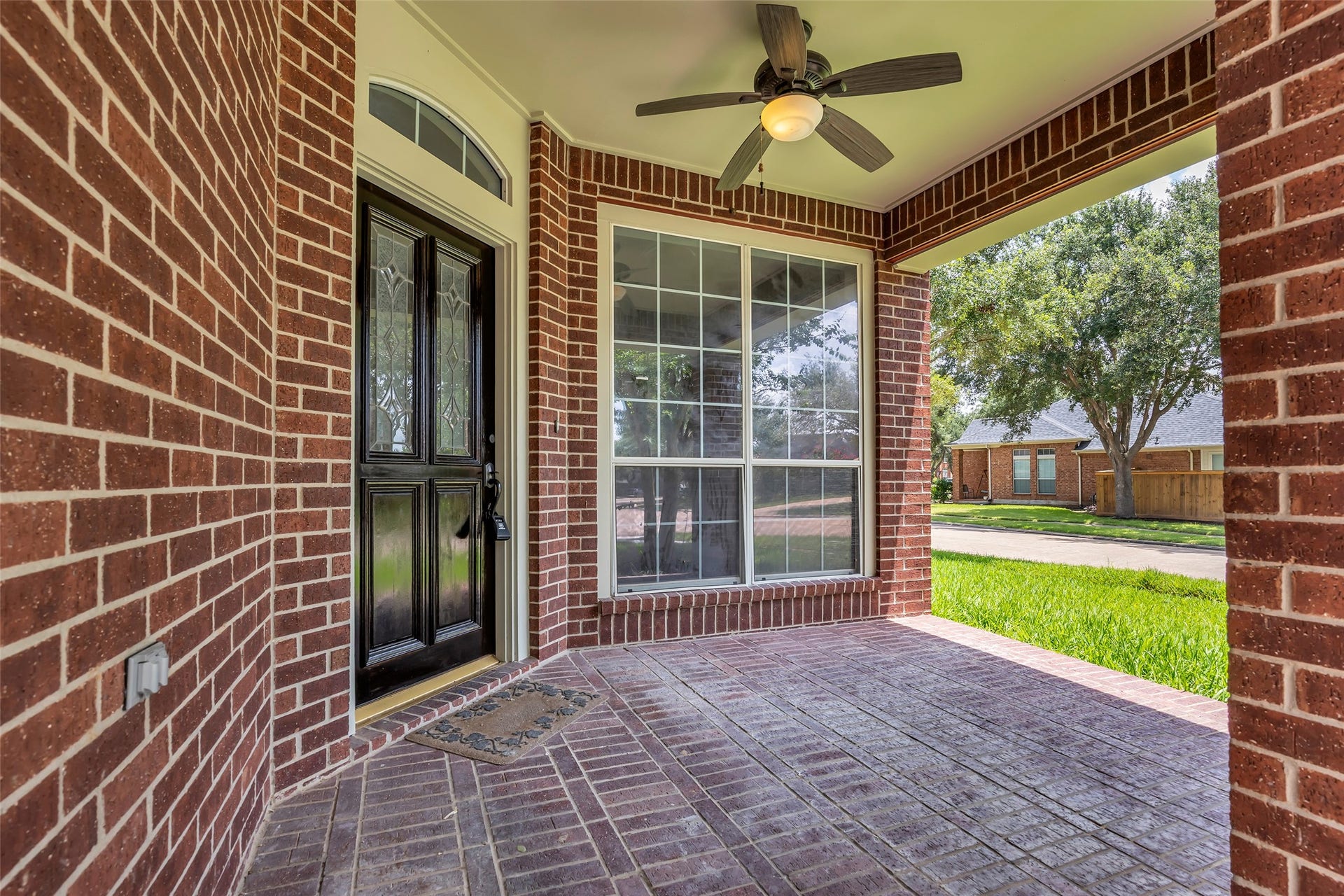 22002 Madera Canyon Court, Richmond, TX 77469 Charming covered porch with elegant brickwork, a stylish front door, and a ceiling fan, offering a welcoming entrance and a cozy spot to enjoy the outdoors.
