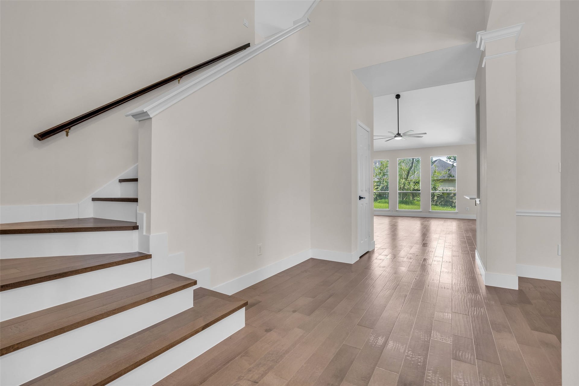 22002 Madera Canyon Court, Richmond, TX 77469 Step into this inviting home featuring a bright, open entryway with elegant wood flooring and a modern staircase, leading to a spacious living area with large windows that offer serene views of the lush backyard.