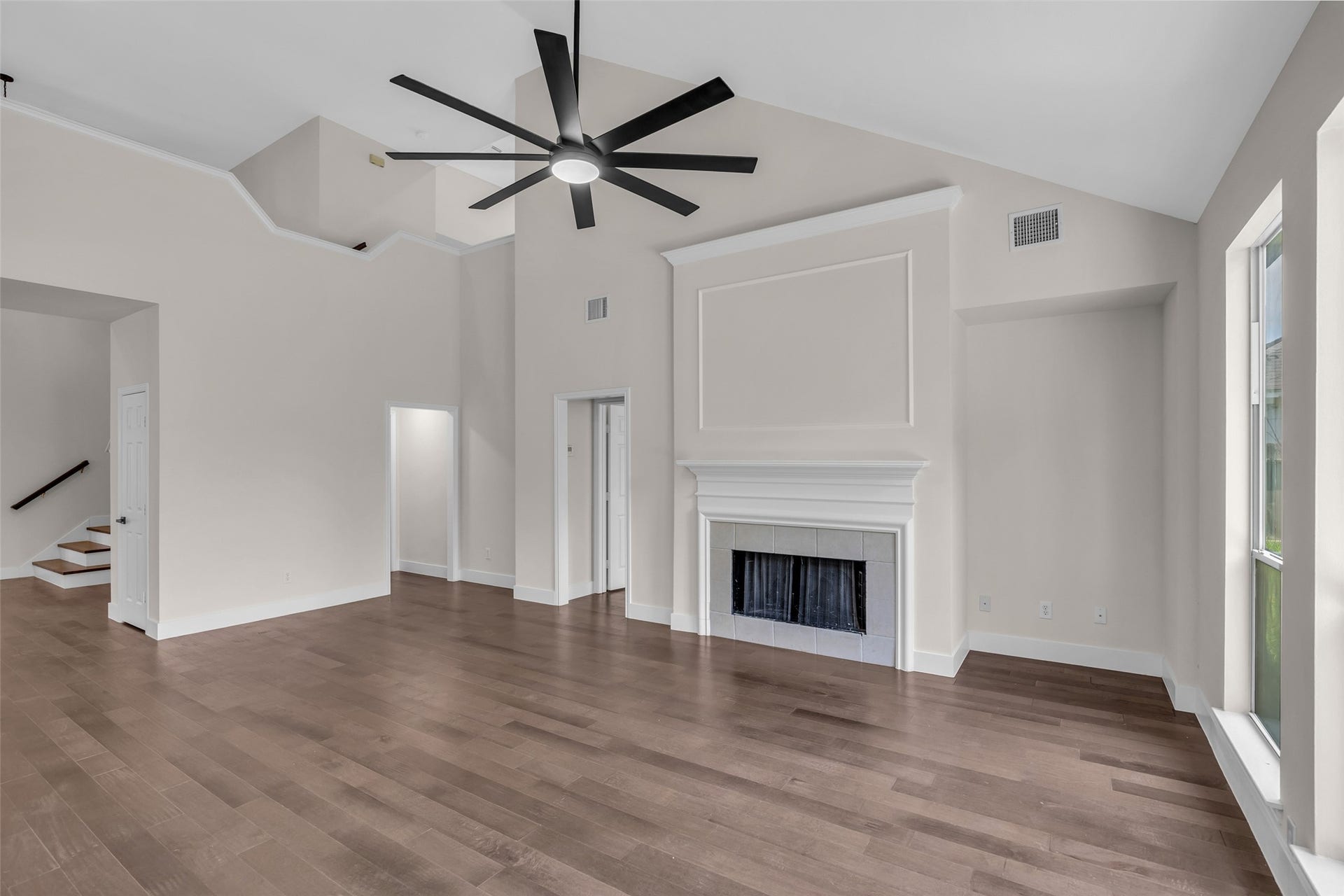 22002 Madera Canyon Court, Richmond, TX 77469 Spacious living room with high ceilings, a sleek modern ceiling fan, elegant fireplace, and abundant natural light from large windows, perfect for relaxation and entertaining.