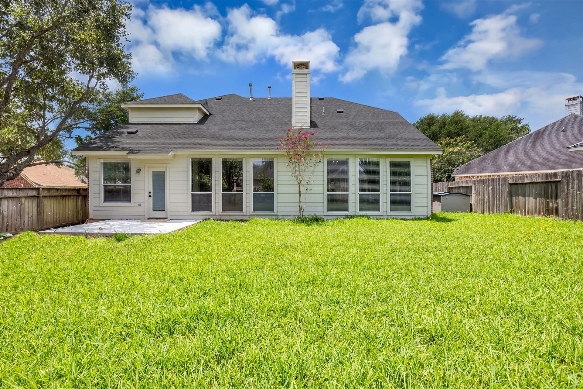 22002 Madera Canyon Court, Richmond, TX 77469 Charming residence featuring a spacious backyard with lush green lawn, large windows for ample natural light, and a cozy patio for outdoor relaxation.