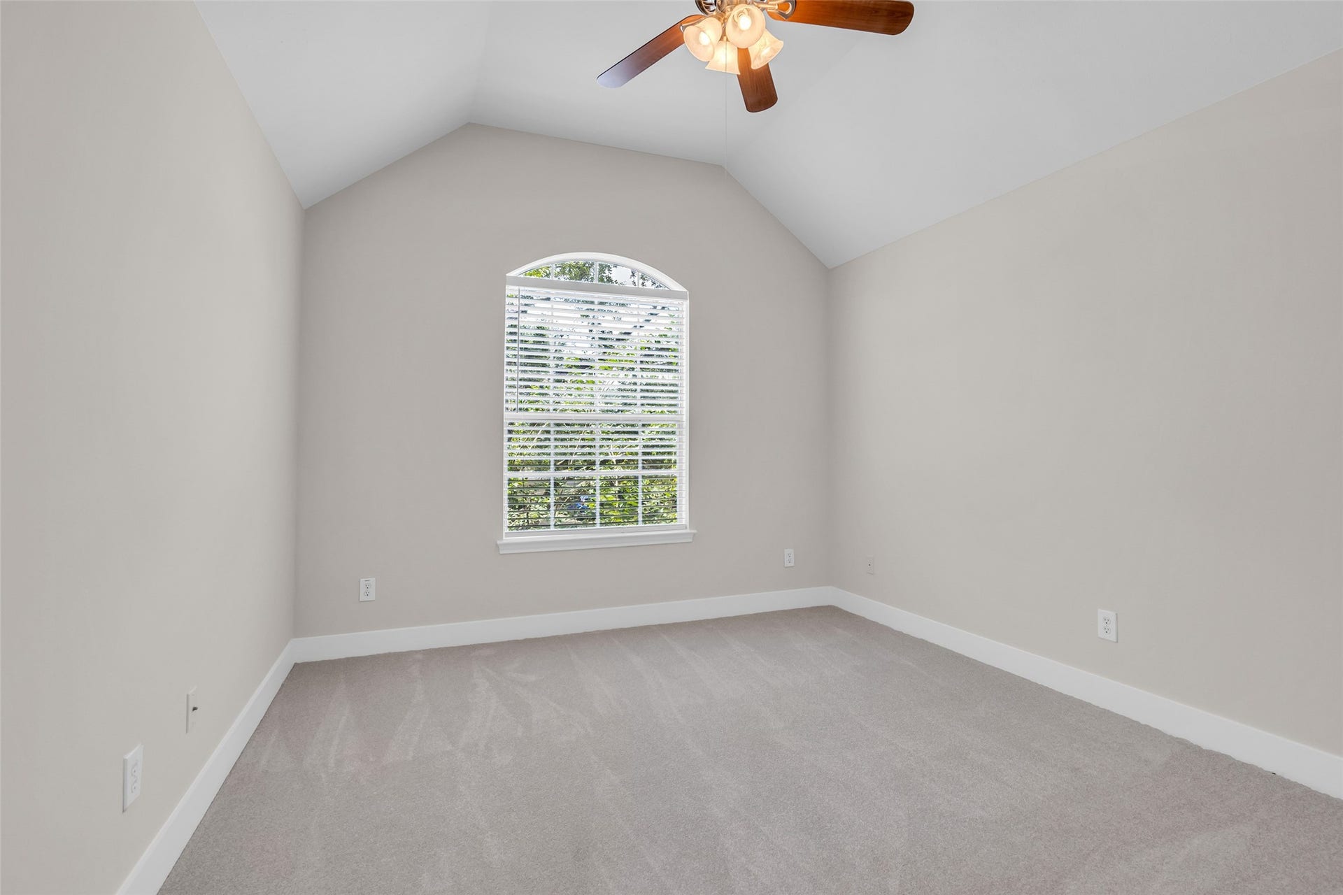 22002 Madera Canyon Court, Richmond, TX 77469 Bright and airy second bedroom featuring a vaulted ceiling, large arched window, and a modern ceiling fan, offering a serene and cozy atmosphere.