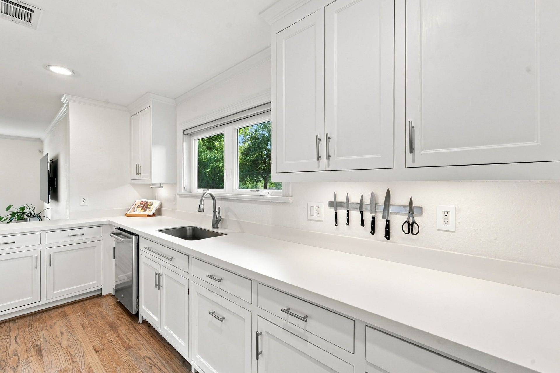 White shaker cabinets and a deep run of counter under the sink window.