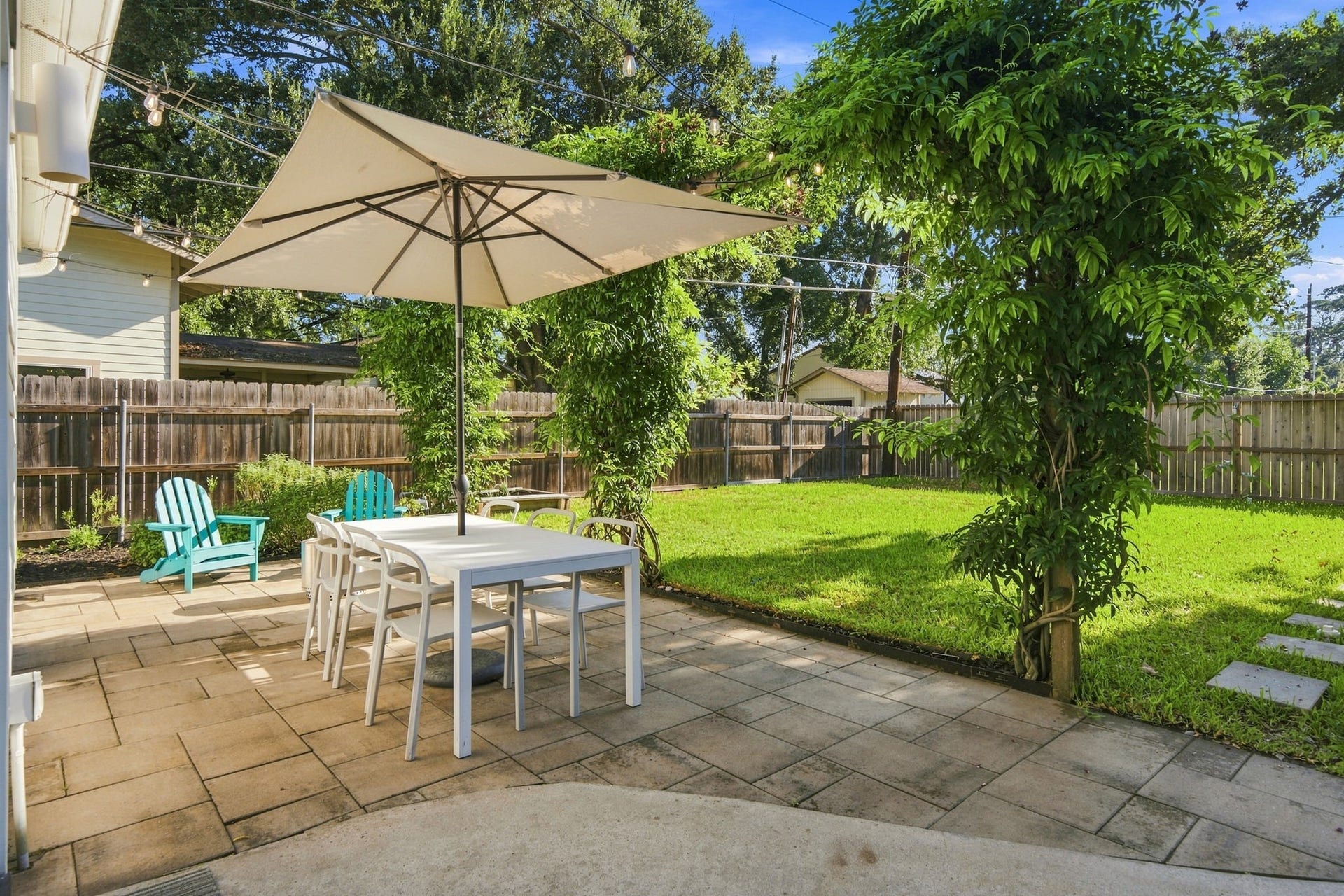 Back deck rebuilt 2026. Dining under the oak canopy with the deep, shaded yard behind it.