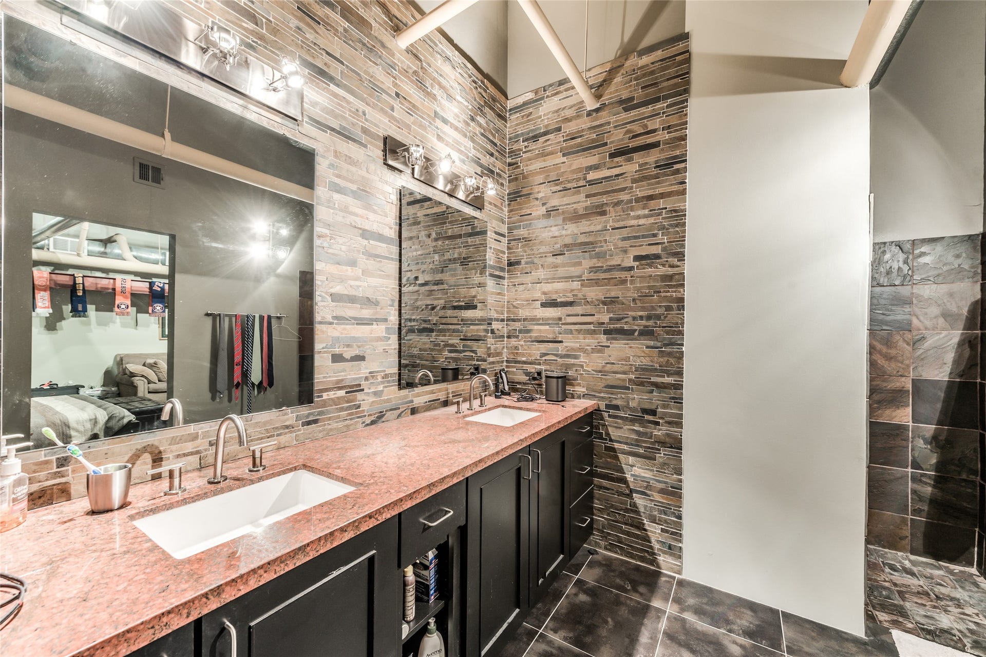 705 Main Street, #215, Houston, TX 77002 This modern bathroom features a dual-sink vanity with sleek granite countertops and dark cabinetry.