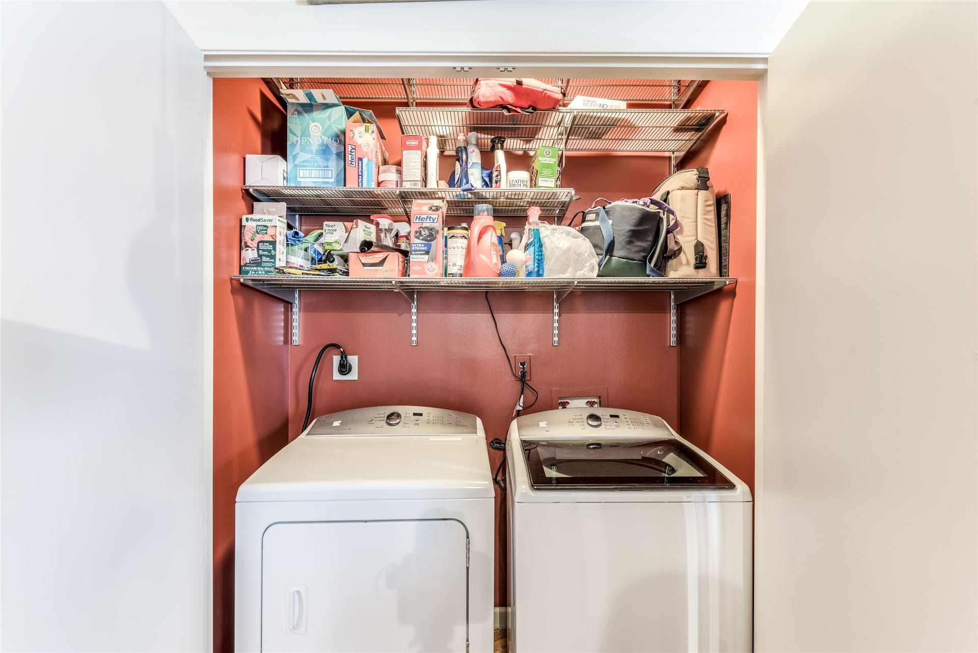 705 Main Street, #215, Houston, TX 77002 Compact laundry nook with a washer and dryer below two shelves stocked with various household supplies. Ideal for efficient use of space.