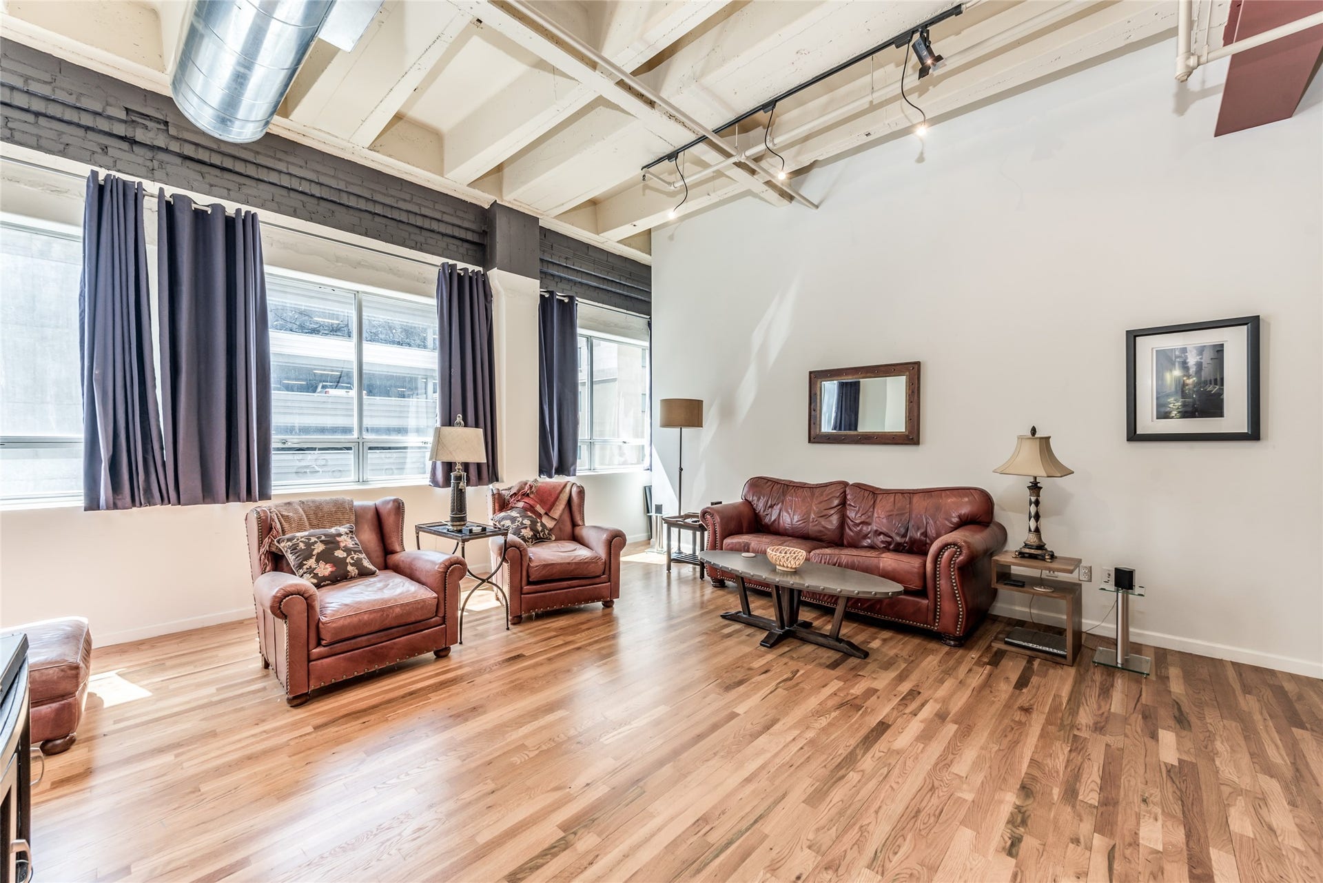 705 Main Street, #215, Houston, TX 77002 This spacious living room features a modern industrial vibe with exposed ductwork, high ceilings, and large windows for ample natural light.