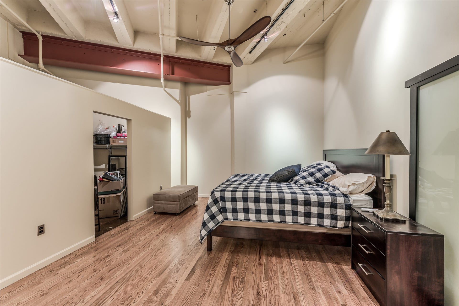 705 Main Street, #215, Houston, TX 77002 This photo features a bedroom with a modern industrial vibe, highlighted by exposed beams and a ceiling fan.