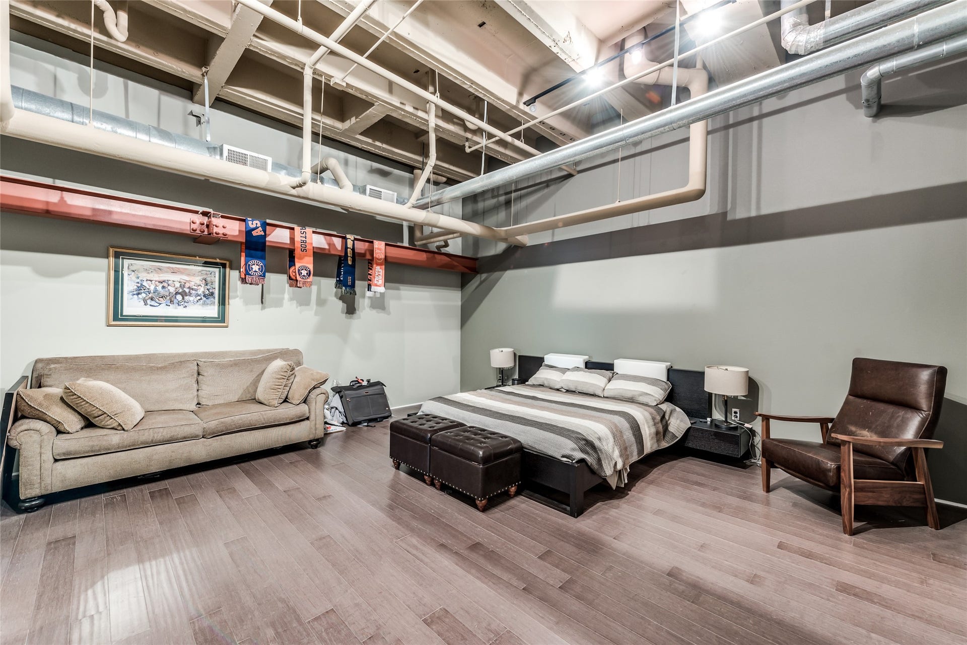 705 Main Street, #215, Houston, TX 77002 This loft-style primary bedroom features exposed ductwork and beams for an industrial feel.