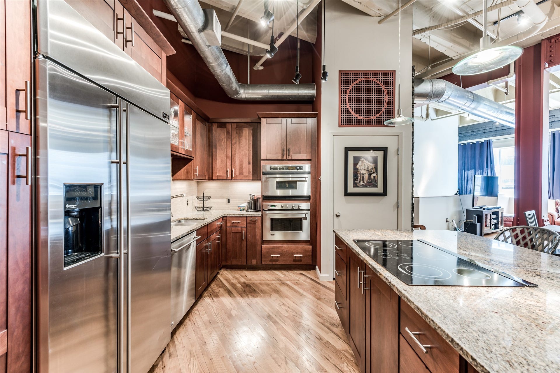 705 Main Street, #215, Houston, TX 77002 This modern kitchen features stainless steel appliances, wood cabinetry, and a spacious granite island with an electric cooktop.