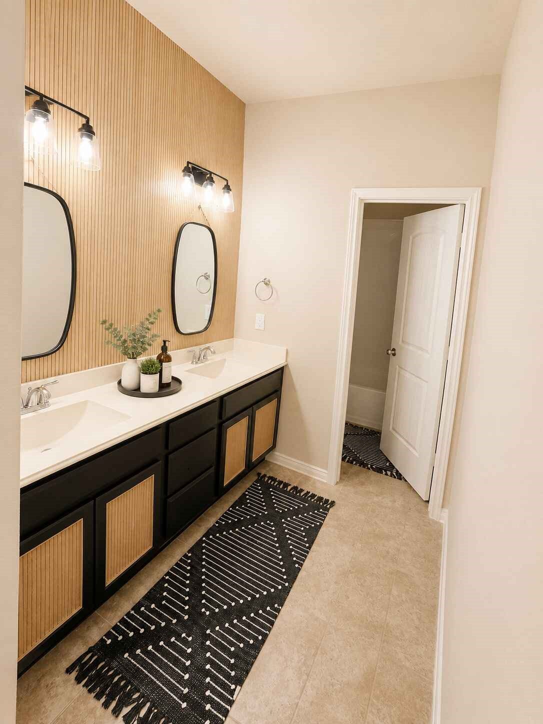 21570 Spear Valley Lane, Porter, TX 77365 Stylishly updated secondary bath features a dual-sink vanity, modern black cabinetry, decorative wood accents, contemporary mirrors and updated lightingplenty of space for busy mornings
