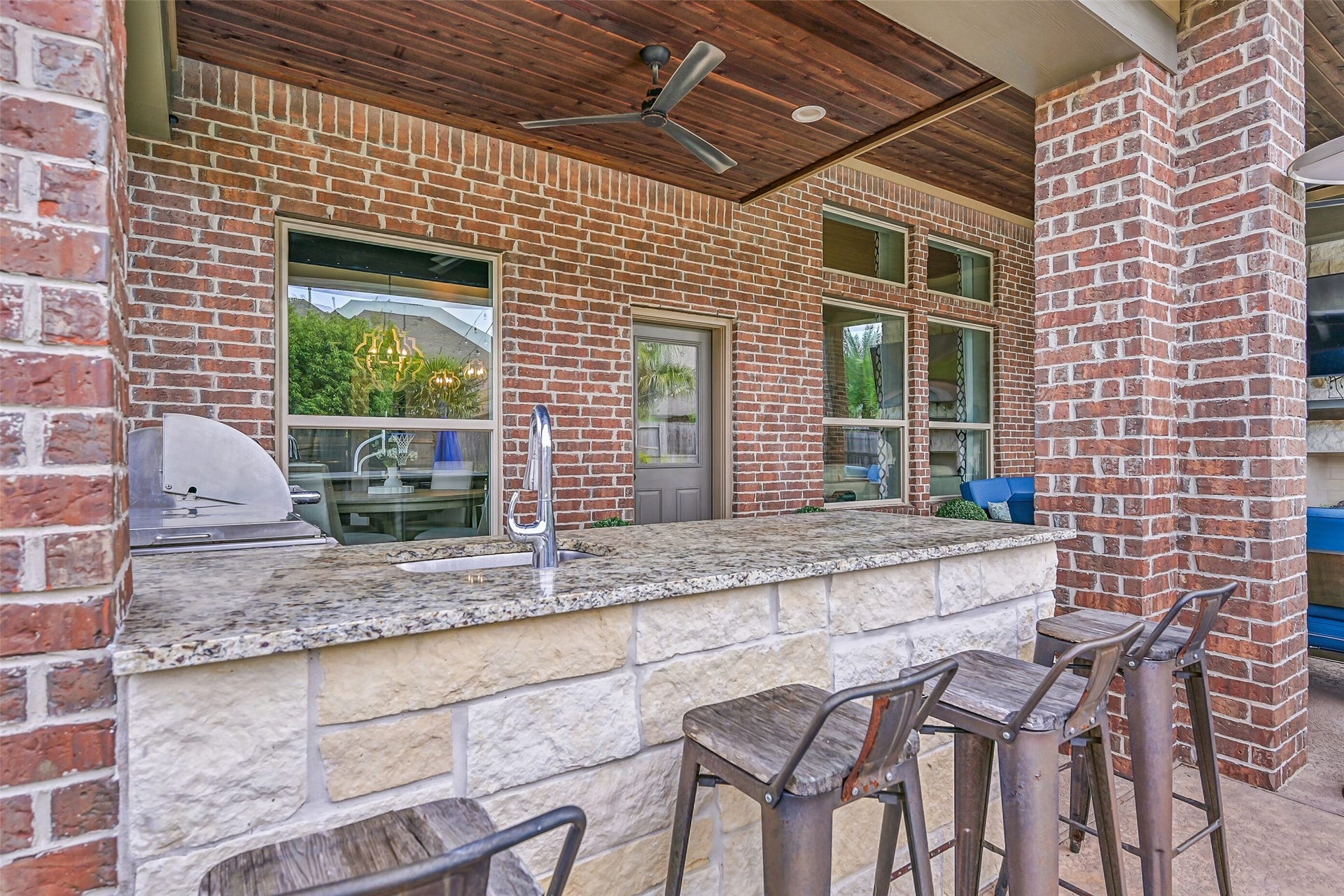 The granite-topped outdoor kitchen extends into a spacious bar with seating, creating an ideal connection between the cooking and lounging areas. Stainless outdoor kitchen appliances are included with the home.