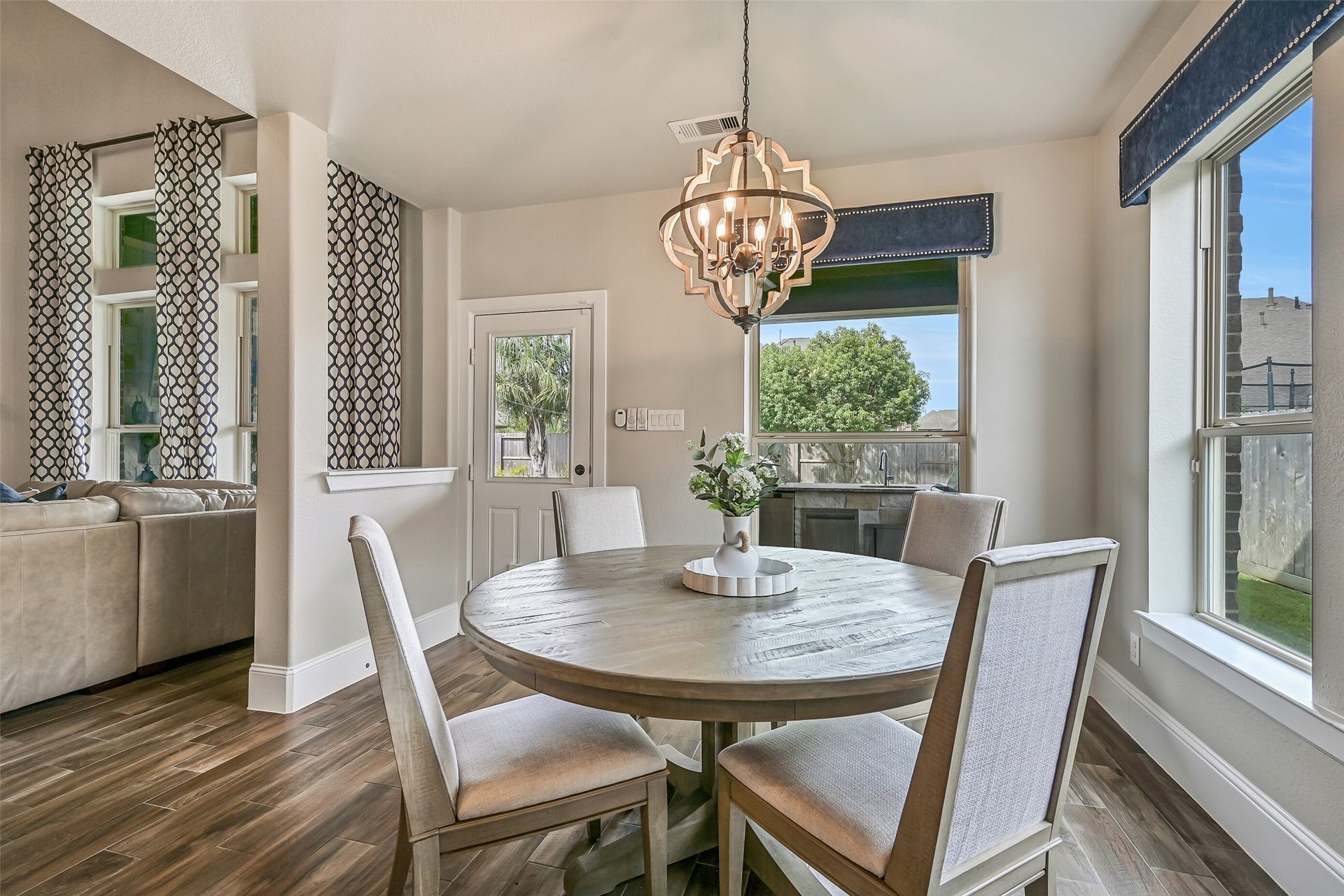 The bright breakfast room is surrounded by windows and features updated lighting, custom window treatments and convenient backyard accessjust steps from the kitchen and outdoor living area.