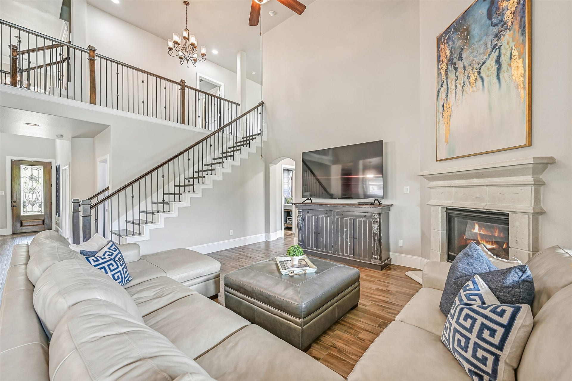 Soaring 19' ceilings make an immediate impression in the spacious family room, where wood-look tile floors, a cast-stone gas-log fireplace and wood-tread staircase with iron balusters add warmth and architectural interest.