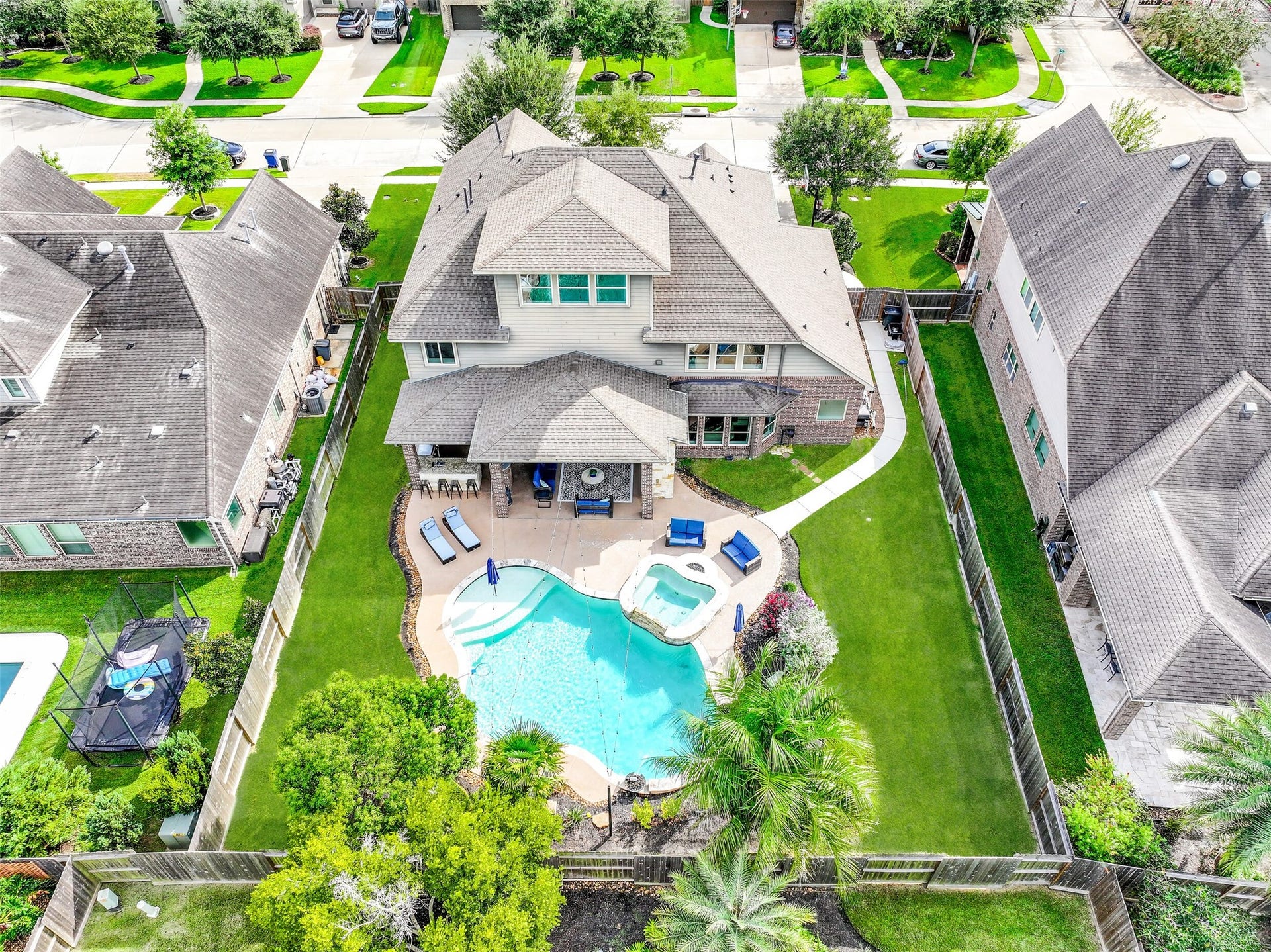 A birds-eye view showcases the entire backyard retreat, including the heated pool & oversized spa, expansive covered outdoor living area, generous lawn and beautifully maintained landscapingall within the privacy of the fenced yard.
