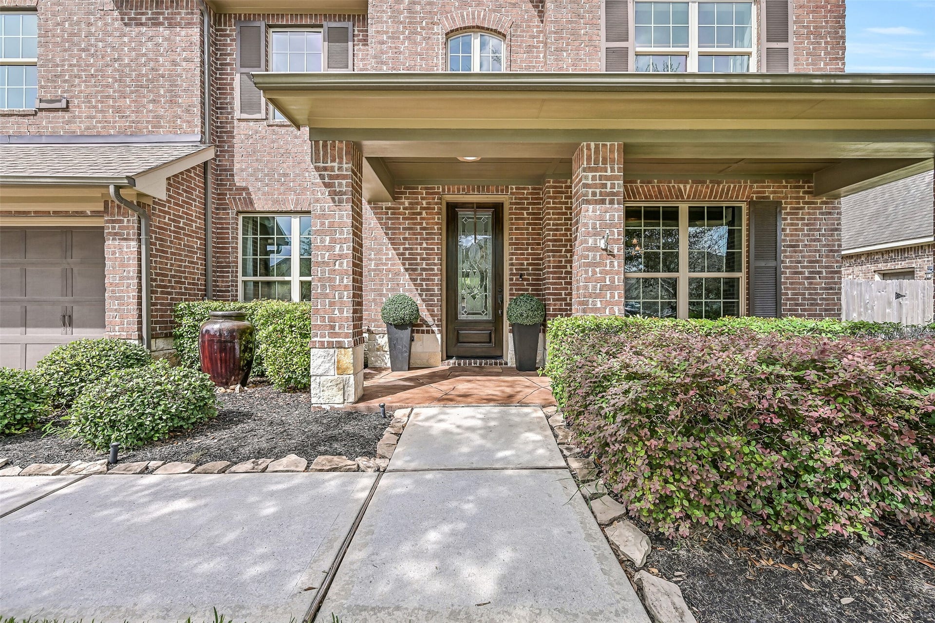 A welcoming covered front porch leads to the decorative glass entry door, surrounded by neatly maintained landscaping. In-ground irrigation helps keep the lawn and landscaping looking their best.