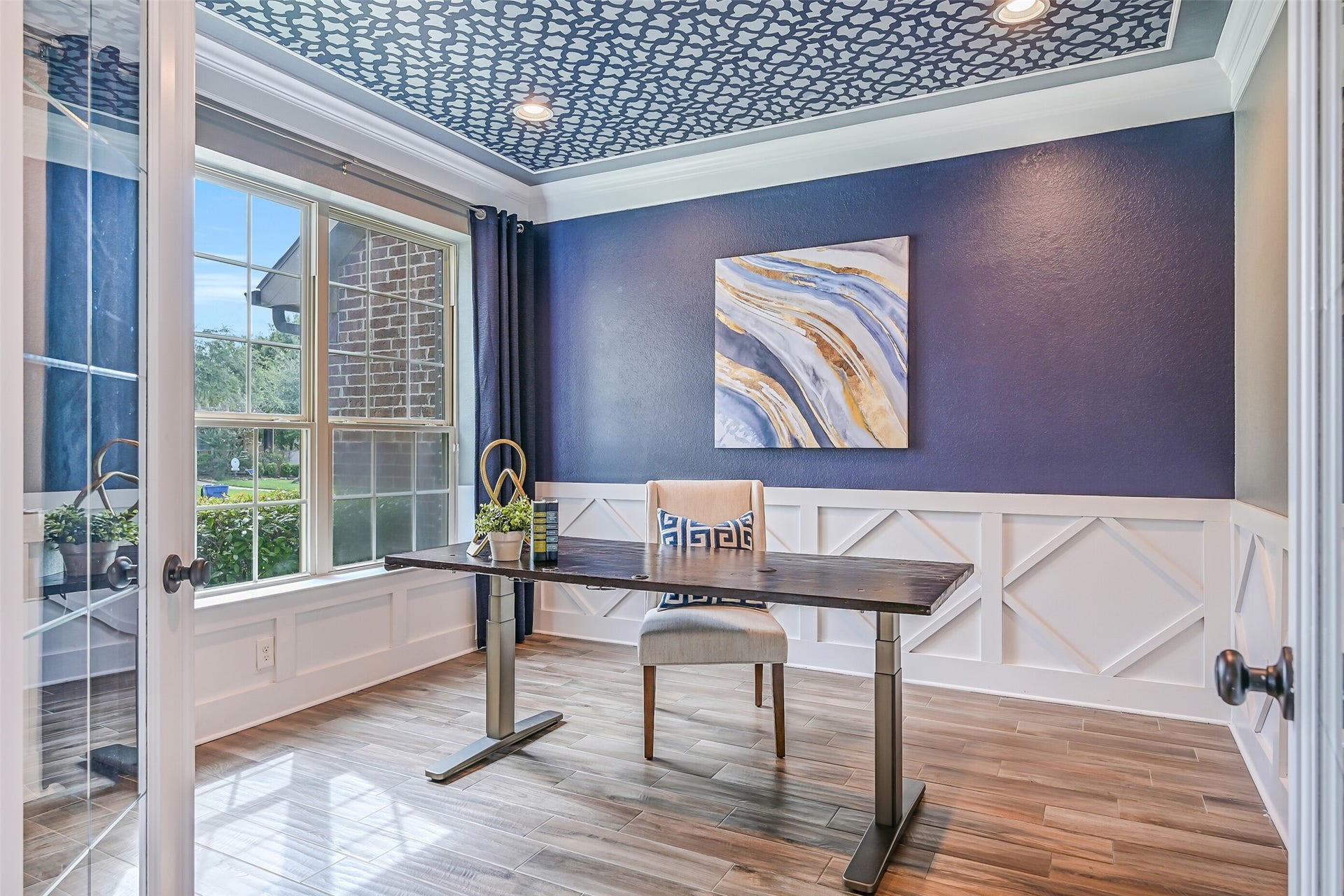 A closer view highlights the study's bold navy accent wall, geometric white millwork and custom ceiling treatmenta polished dedicated workspace with plenty of natural light from the front-facing windows.