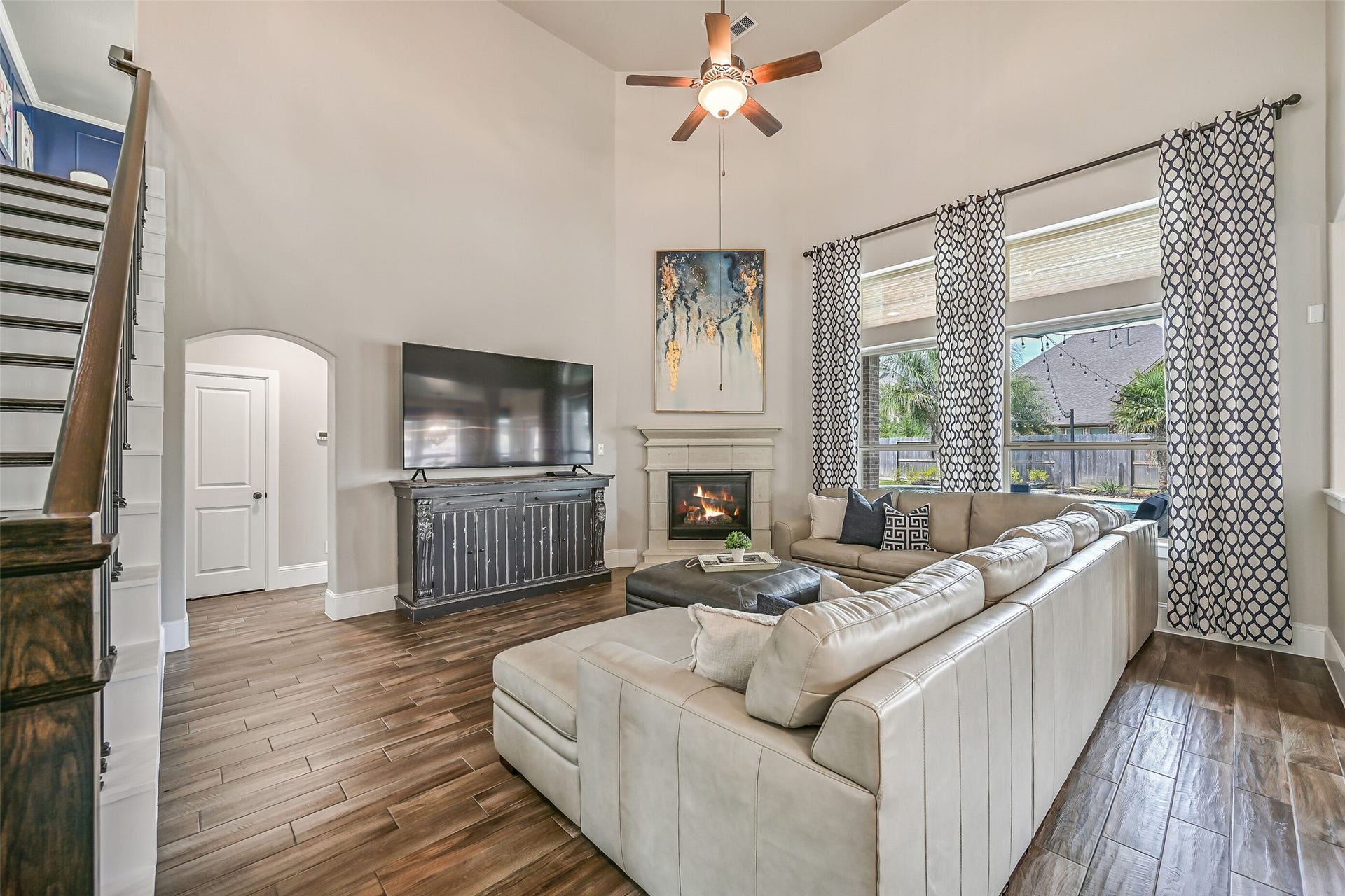 A wall of tall windows fills the family room with natural light and offers views of the backyard pool, while the cast-stone gas-log fireplace creates an elegant focal point beneath the dramatic 19' ceiling.