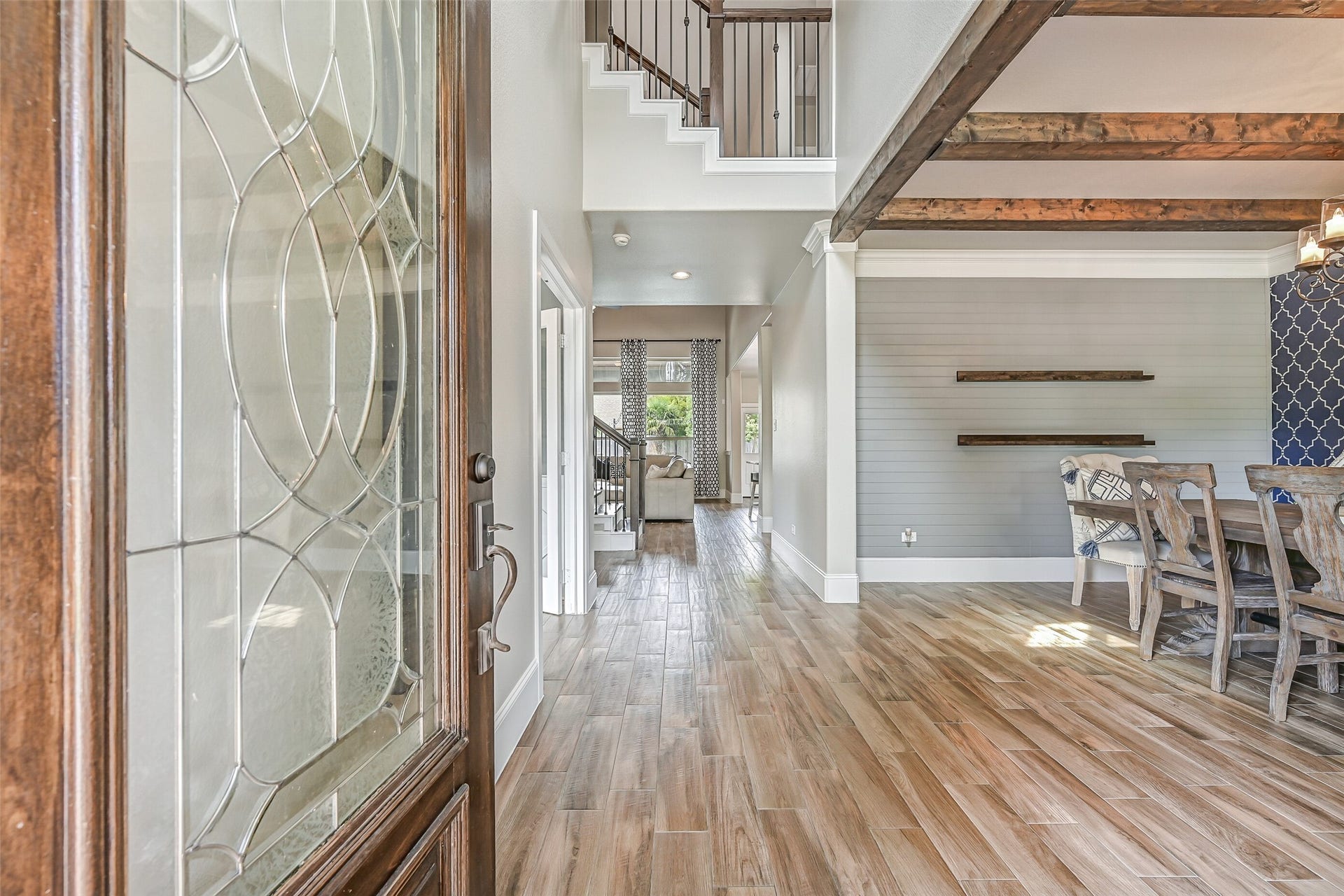 Step inside to wood-look tile flooring and a light-filled floor plan accented by extensive custom details. The dramatic foyer rises to 19' and offers an early glimpse of the beamed dining room and family room beyond.