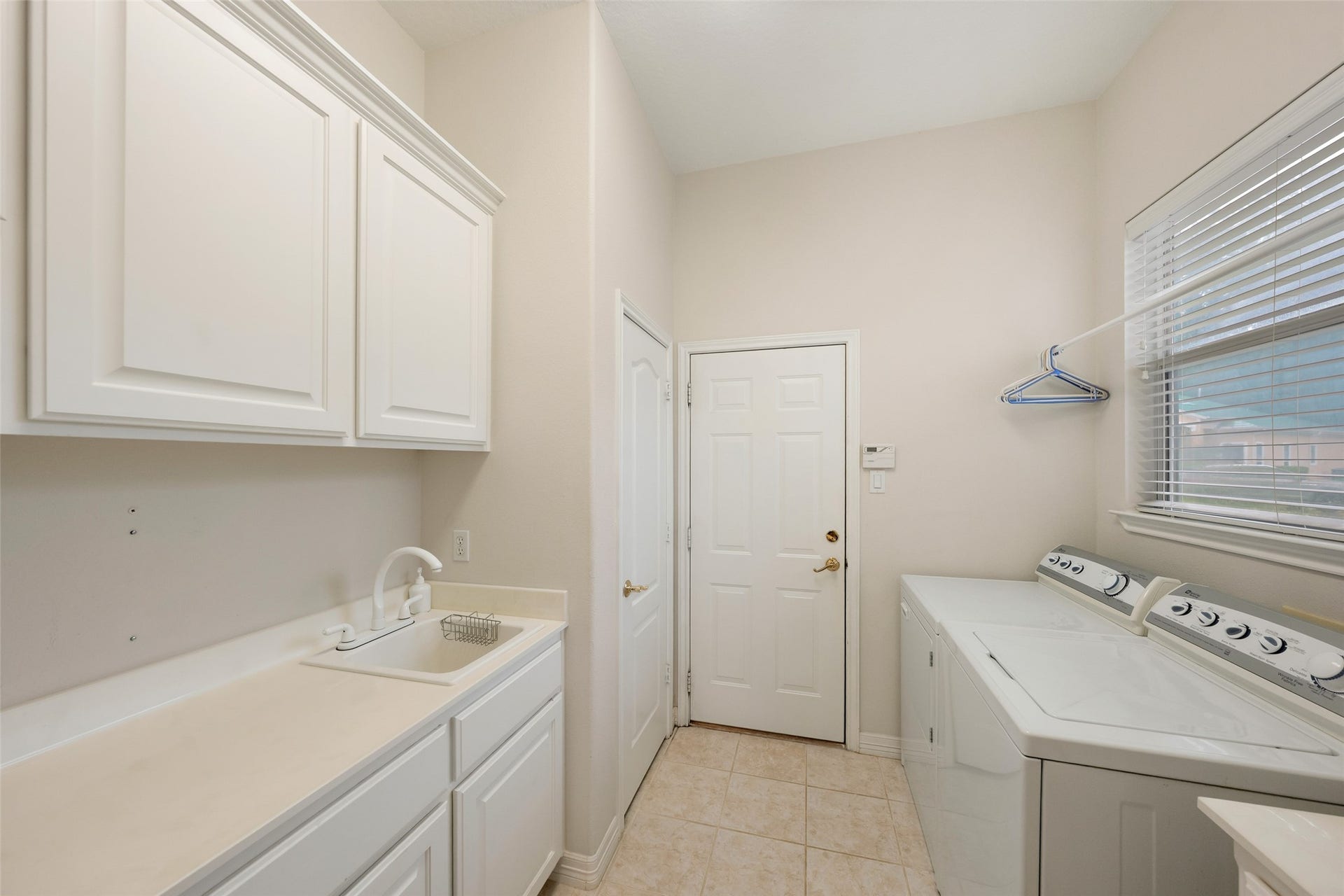 Utility room connects the garage to the kitchen and has loads of cupboards plus a space on which to fold and sort laundry.