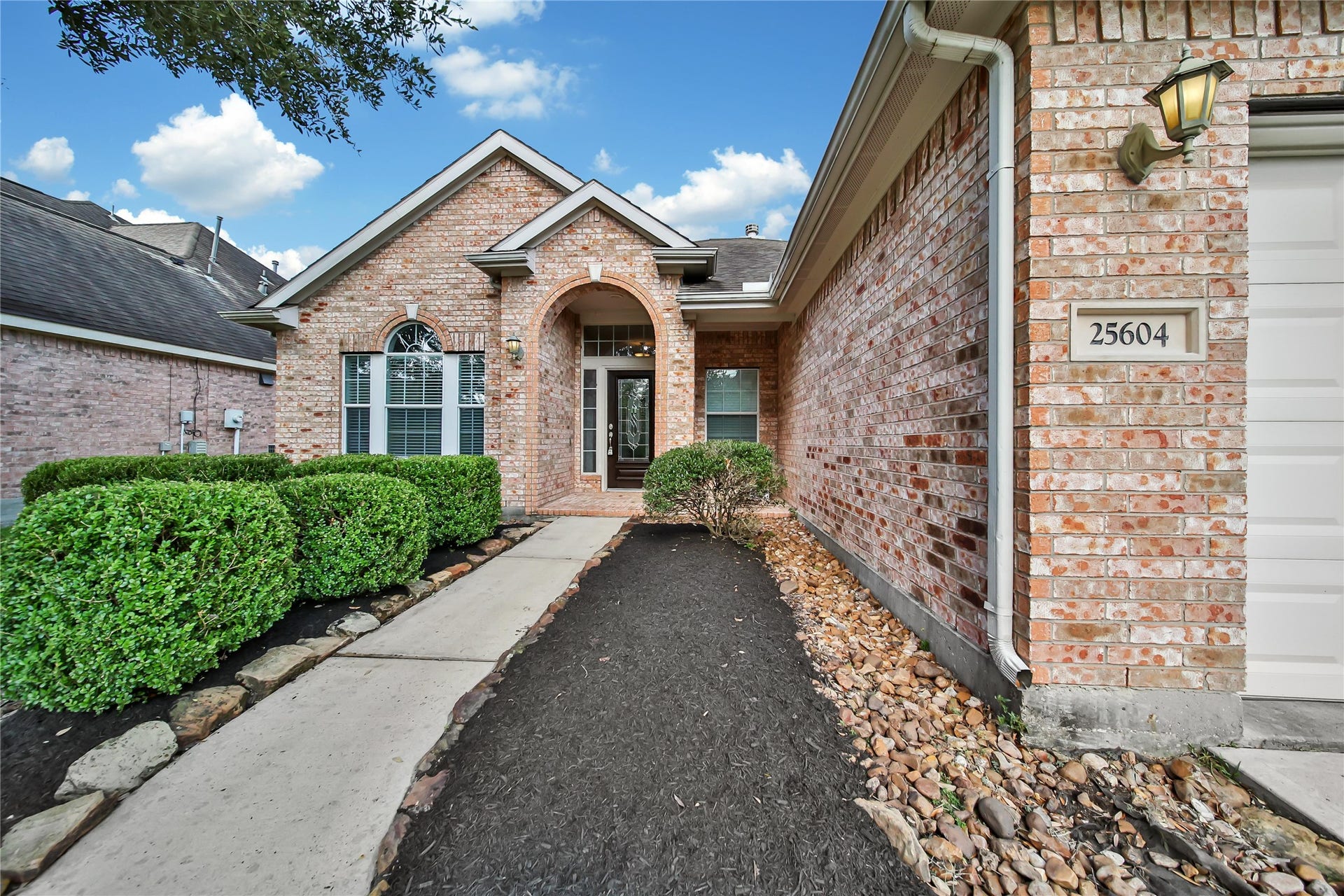 25604 Southwood Oaks Court, Porter, TX 77365 This is a single-story brick home featuring a well-maintained exterior with neat landscaping and a welcoming path leading to an arched entryway. The home has a pitched roof and a large front window, presenting a classic suburban appearance.
