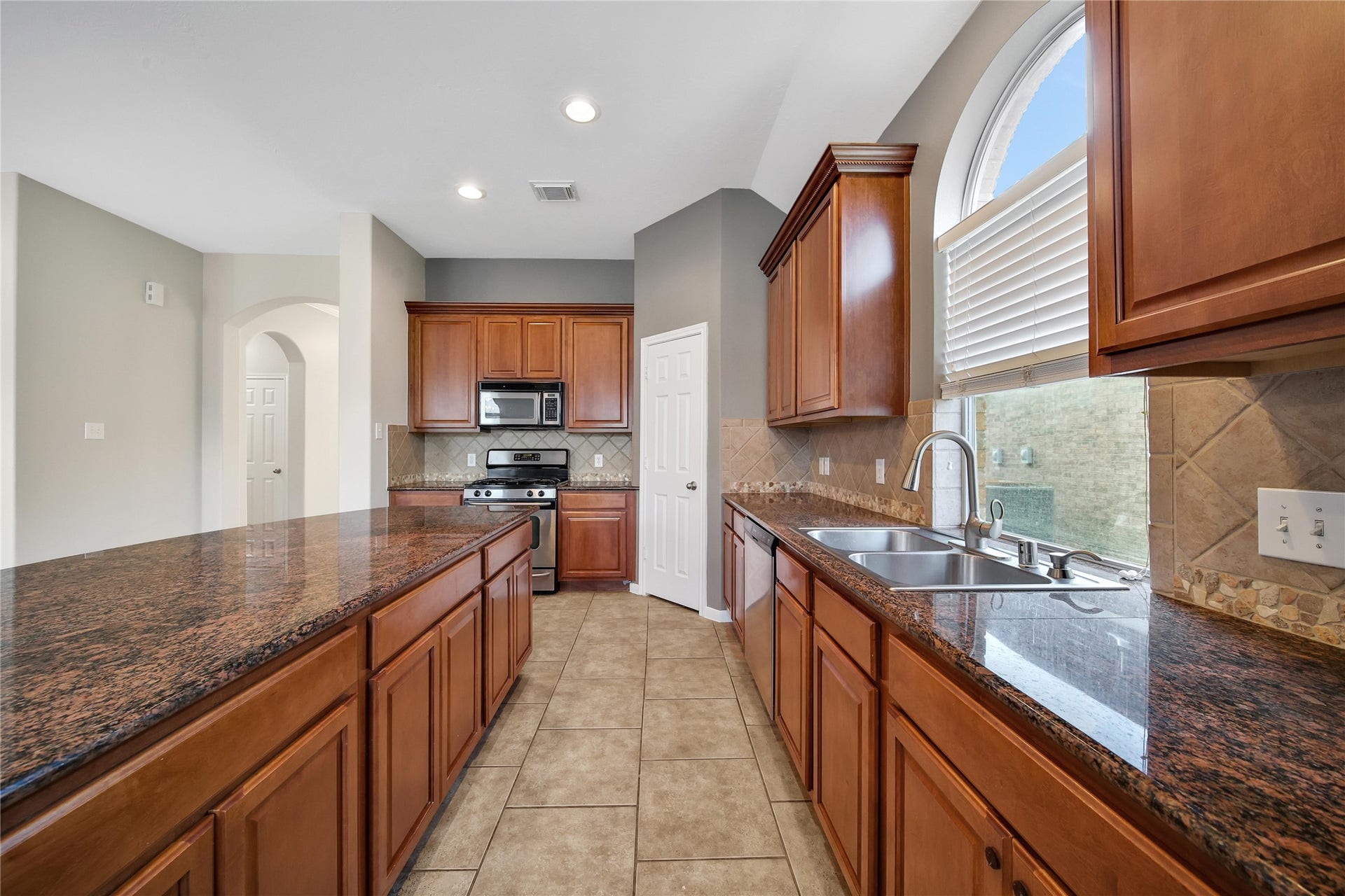 25604 Southwood Oaks Court, Porter, TX 77365 This is a spacious, well-lit kitchen with rich wooden cabinetry and granite countertops, featuring modern appliances and a large window over the sink.