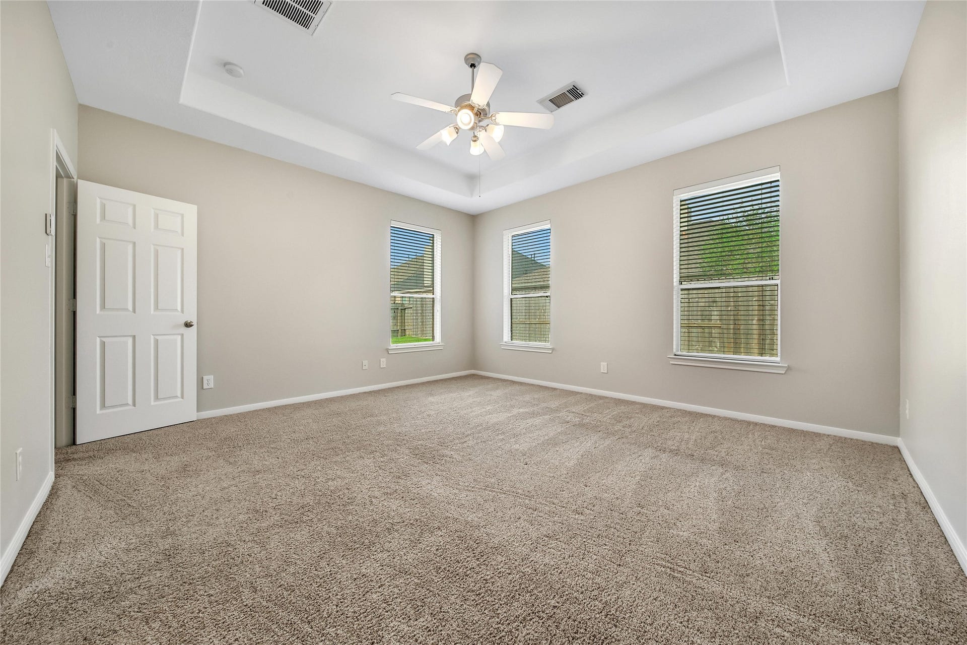 25604 Southwood Oaks Court, Porter, TX 77365 This is a spacious, well-lit Primary Bedroom with neutral walls, carpeting, and a ceiling fan with lighting. It features two large windows that allow for ample natural light.