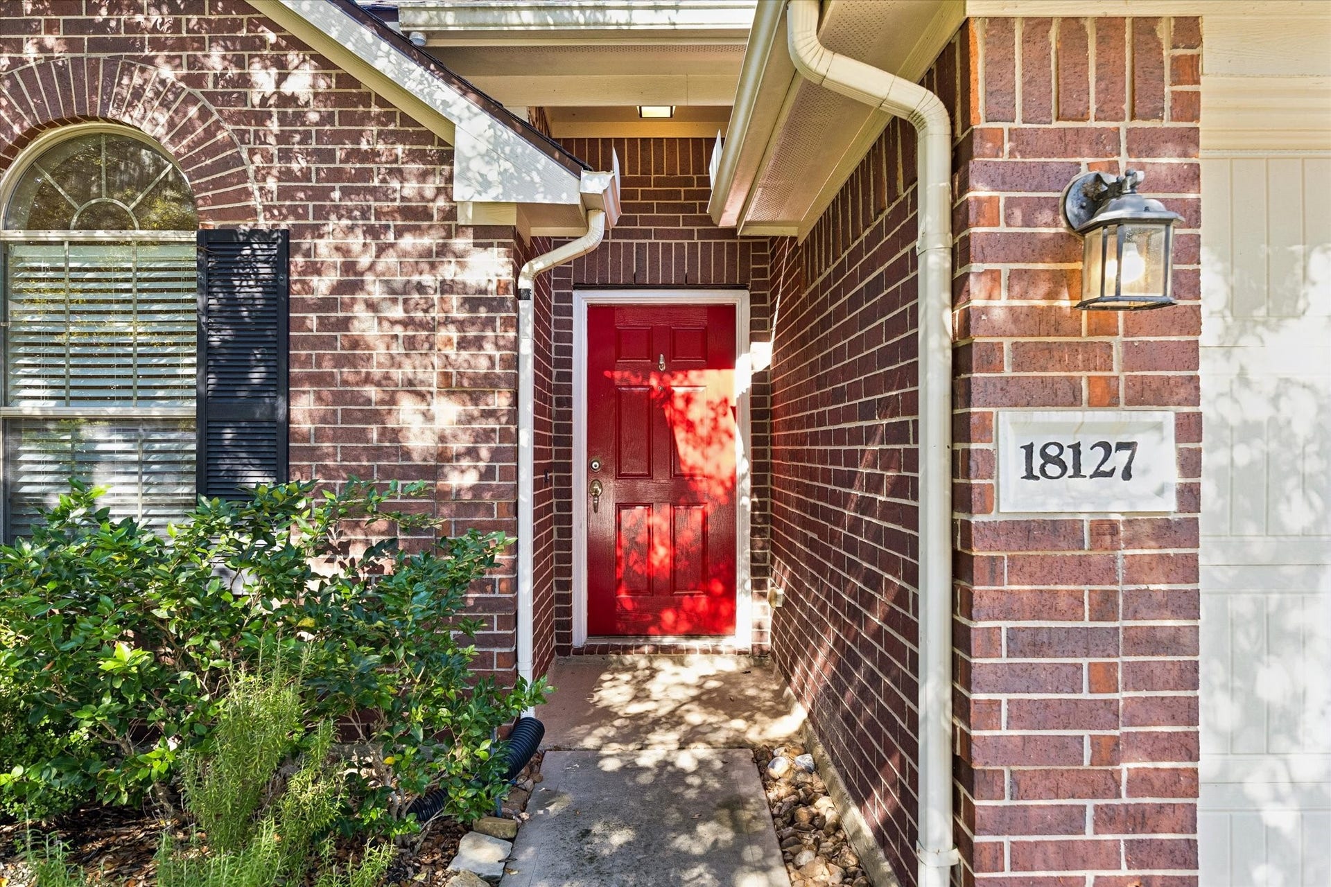 18127 Hillock Glen Lane, Cypress, TX 77429 Inviting covered front entry with a cheerful red front door, decorative shutters, and established landscaping.