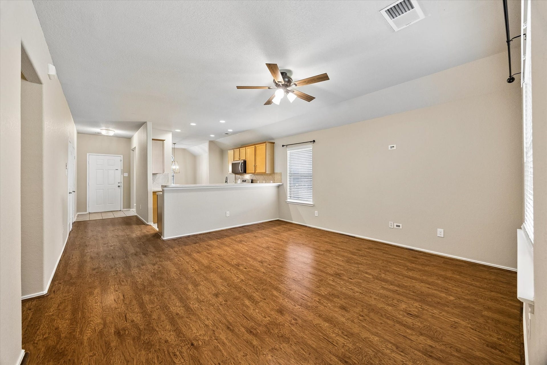 18127 Hillock Glen Lane, Cypress, TX 77429 Open living area featuring wood-look flooring, fresh paint, and a breakfast bar overlooking the main gathering space.