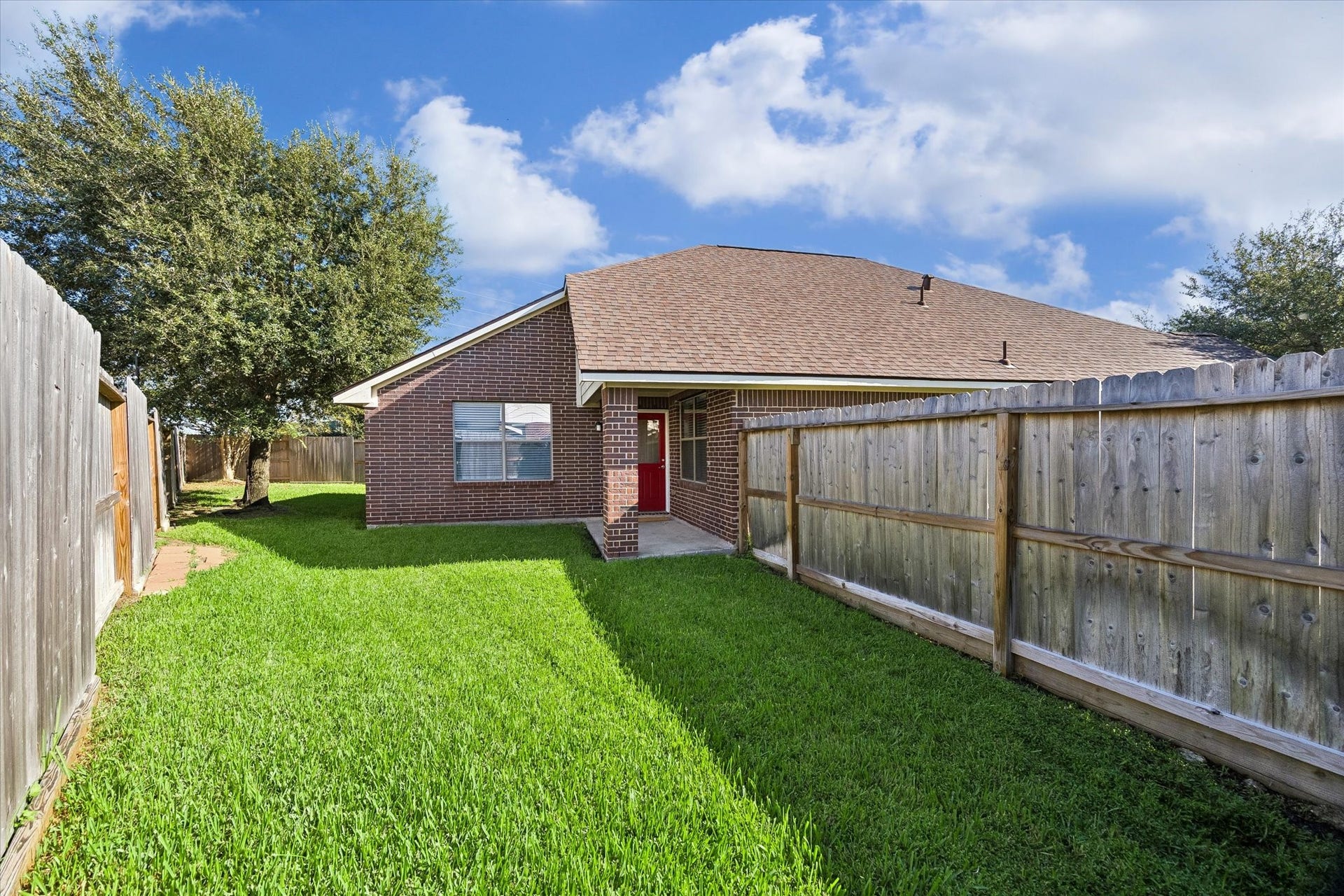 18127 Hillock Glen Lane, Cypress, TX 77429 Rear view of the home showcasing the brick exterior, covered back patio, and fenced backyard.