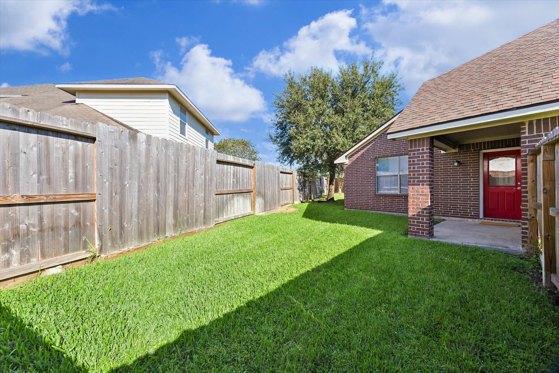 18127 Hillock Glen Lane, Cypress, TX 77429 Fenced backyard featuring a grassy lawn and mature shade tree, offering space for gardening, outdoor activities, or entertaining.