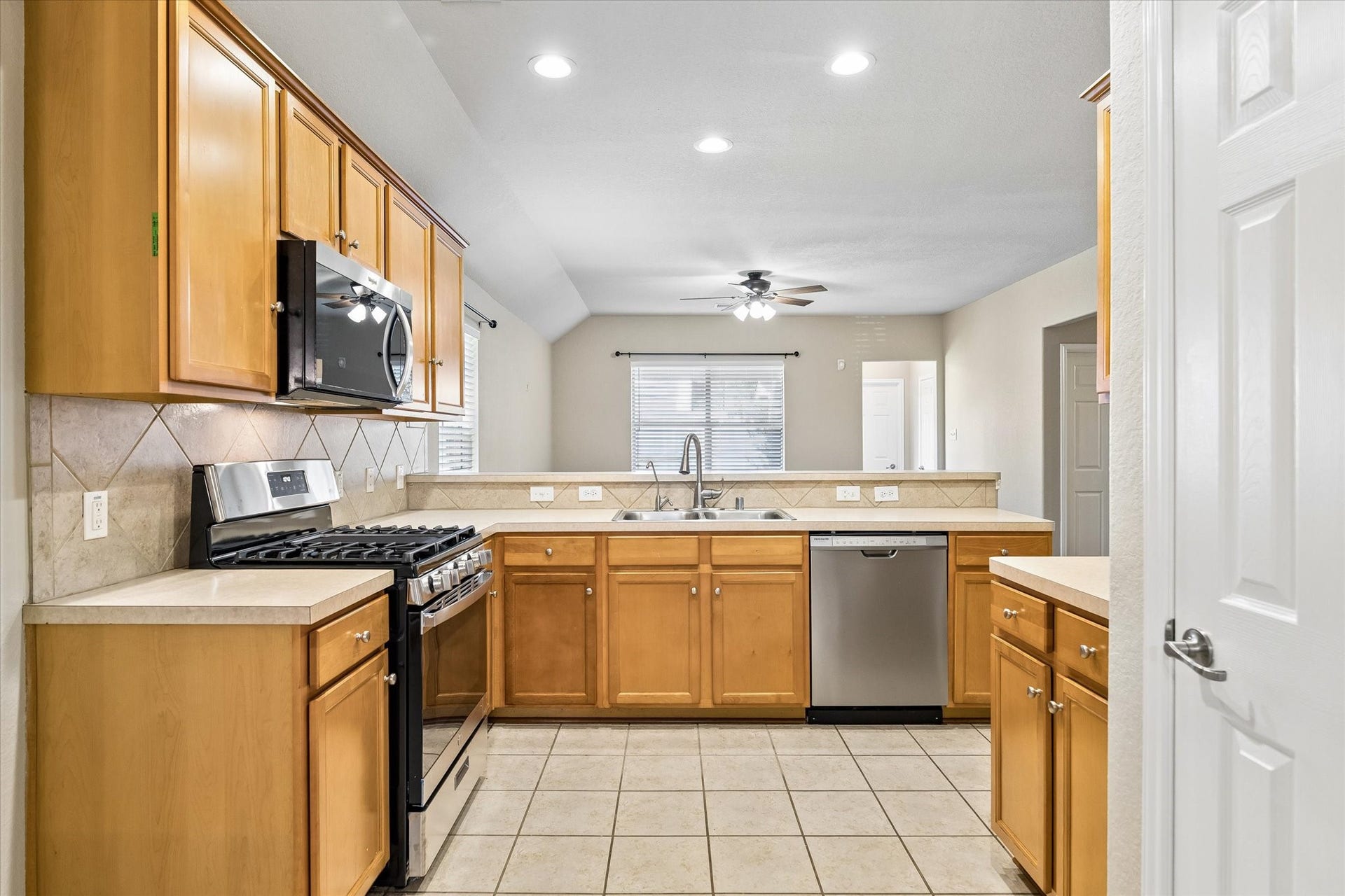 18127 Hillock Glen Lane, Cypress, TX 77429 Functional kitchen featuring a NEW gas range, stainless steel dishwasher, tile backsplash, ample cabinet storage, and breakfast bar.